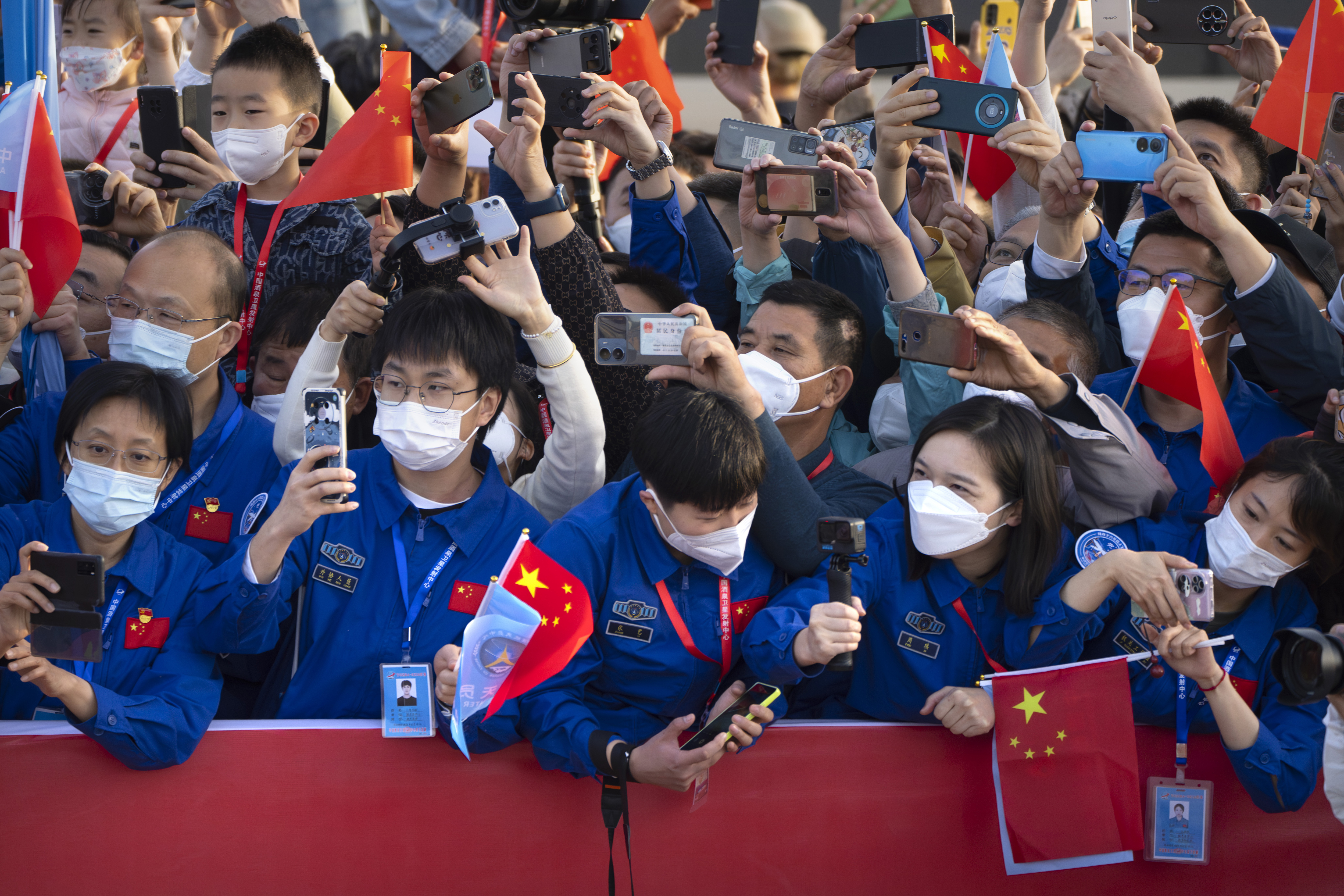 Staff members take photos as Chinese astronauts arrive for a send-off ceremony