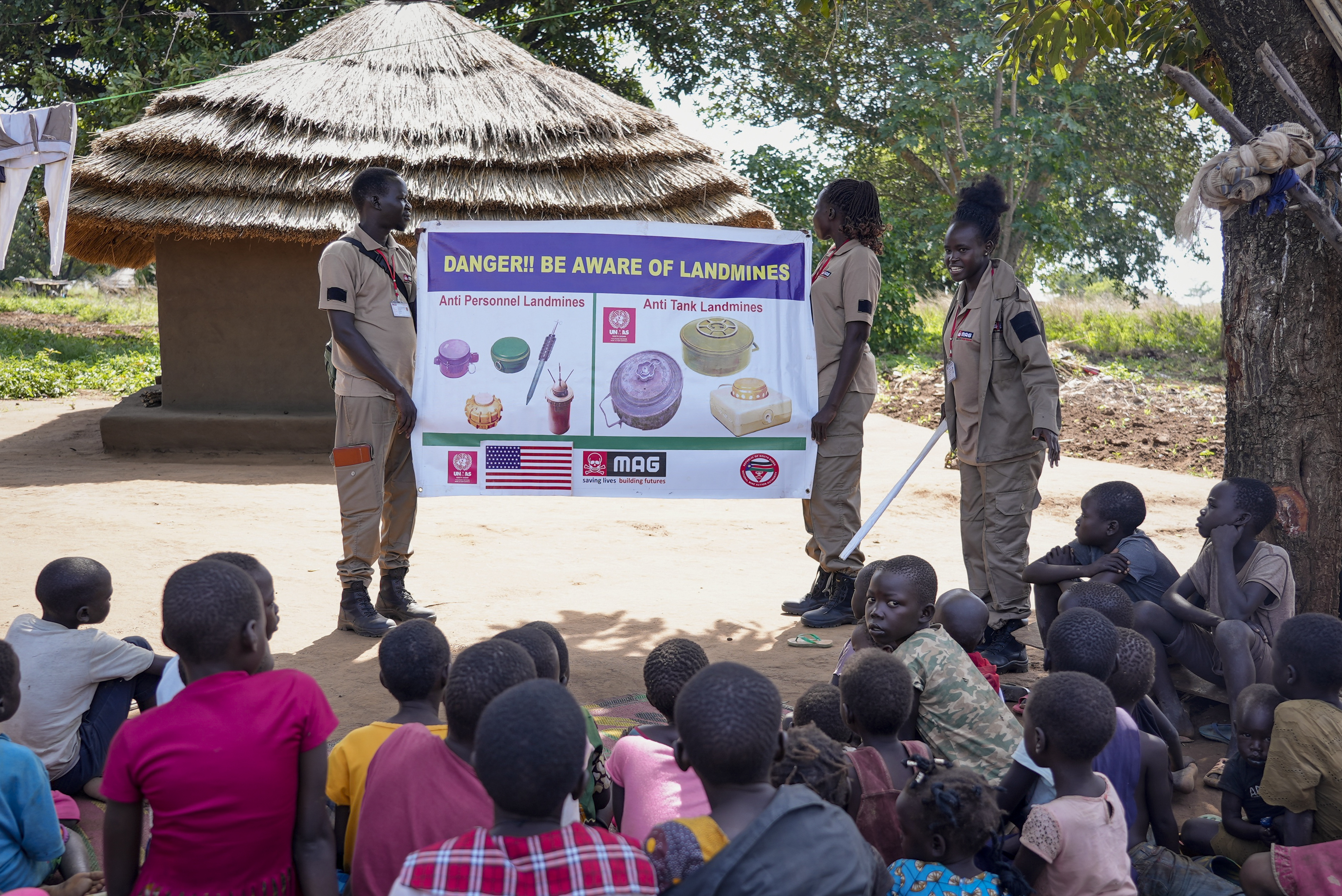 Staff from the Mines Advisory Group (MAG) teach children about the risks of unexploded mines, in Moli village
