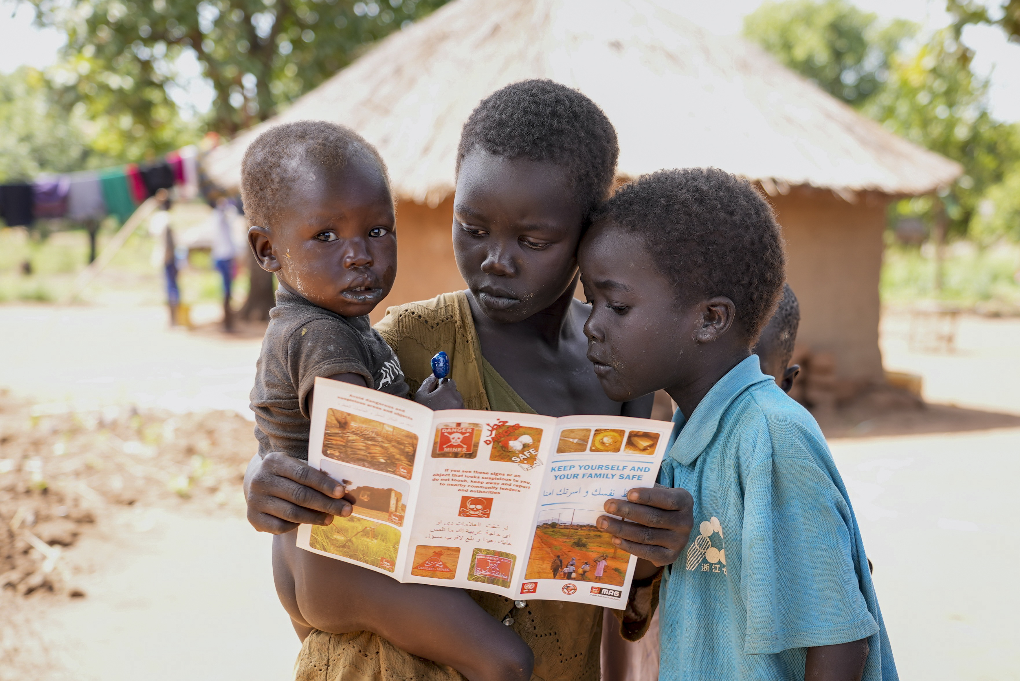 Children read a pamphlet about the dangers of landmines,