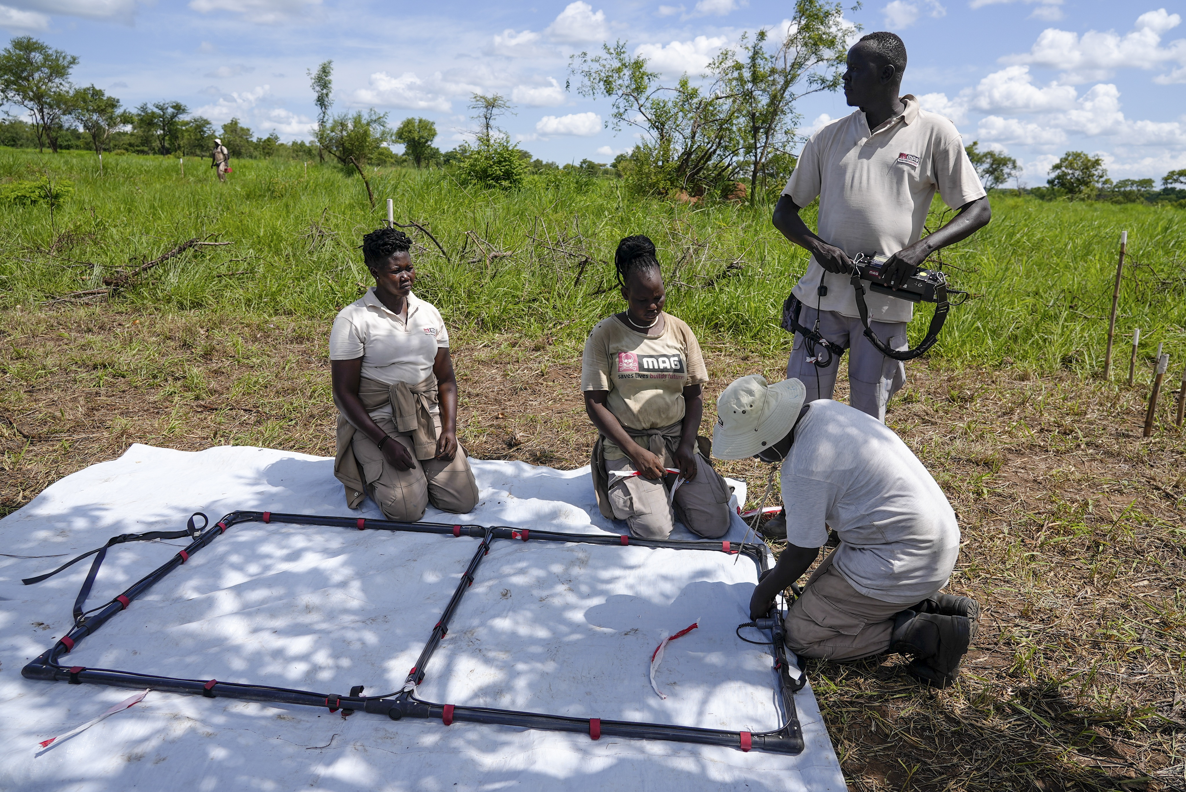 Deminers from the Mines Advisory Group (MAG) prepare to do clearance at a site containing cluster munitions in Ayii