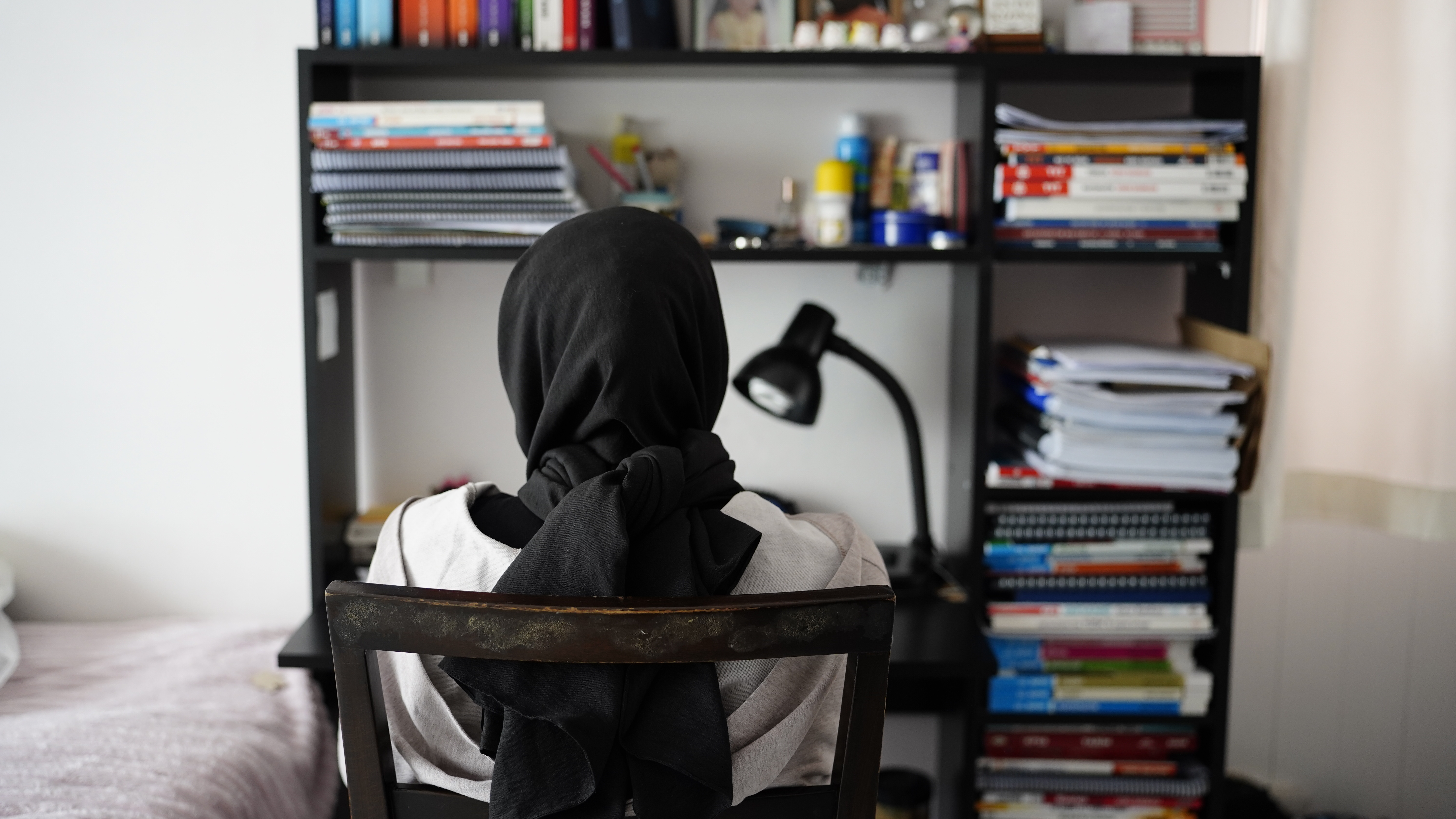 A girl studies at a desk, surrounded by books
