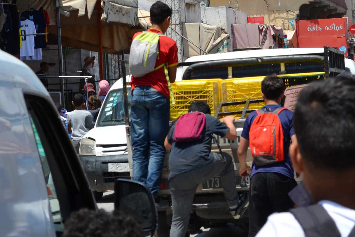 Boys jump on the back of a truck in slow traffic