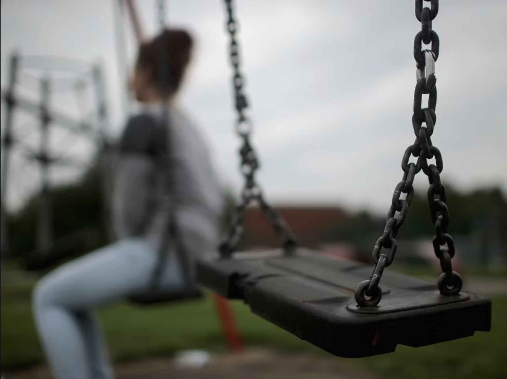 Young girl seen looking away sitting on a swing