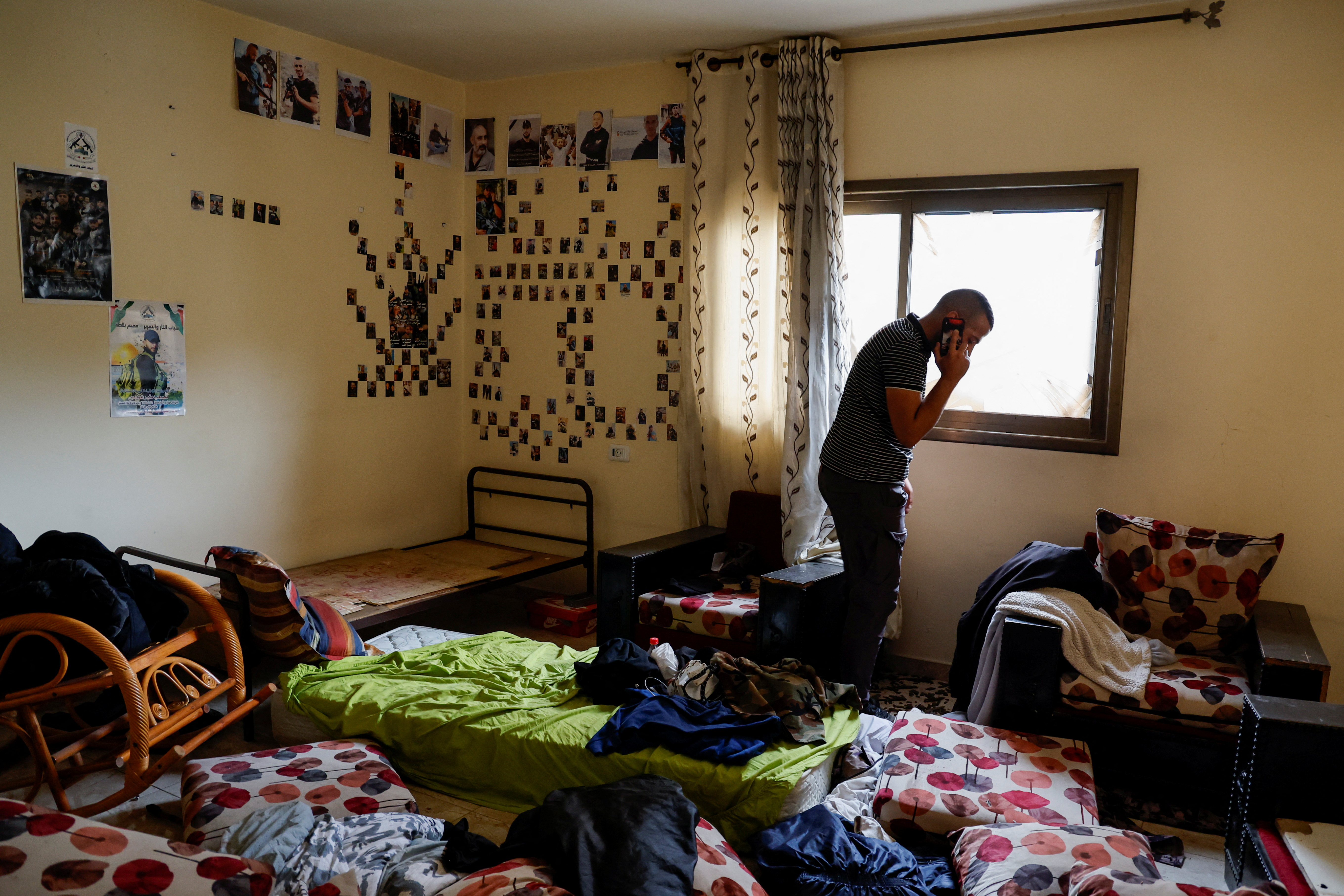 A Palestinian man speaks on the phone in a room with turned over furnishings following an Israeli raid, in Nablus