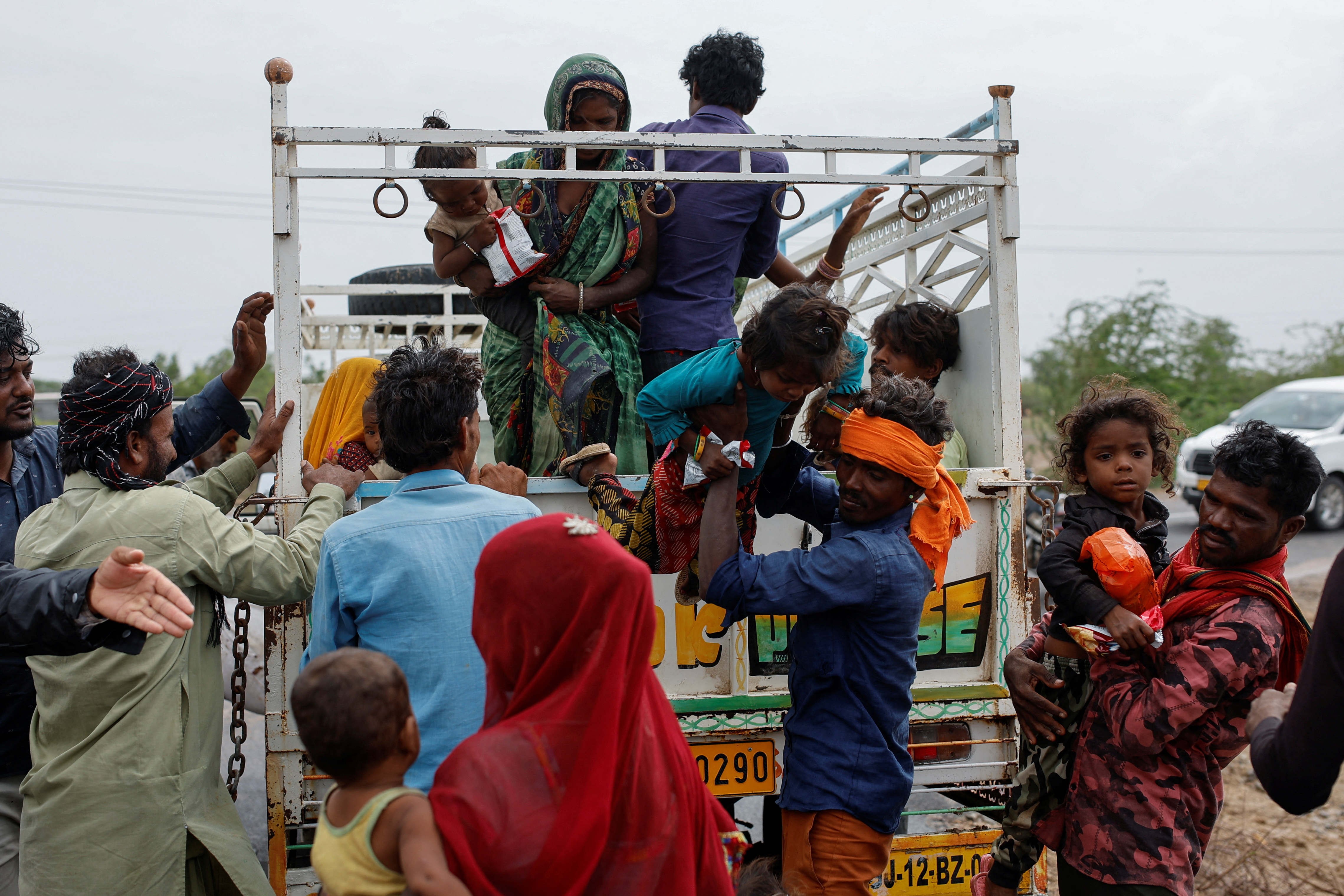 A man carries a child from a truck during an evacuation before the arrival of cyclone Biparjoy in Jakhau in the western state of Gujarat, India, June 14, 2023.