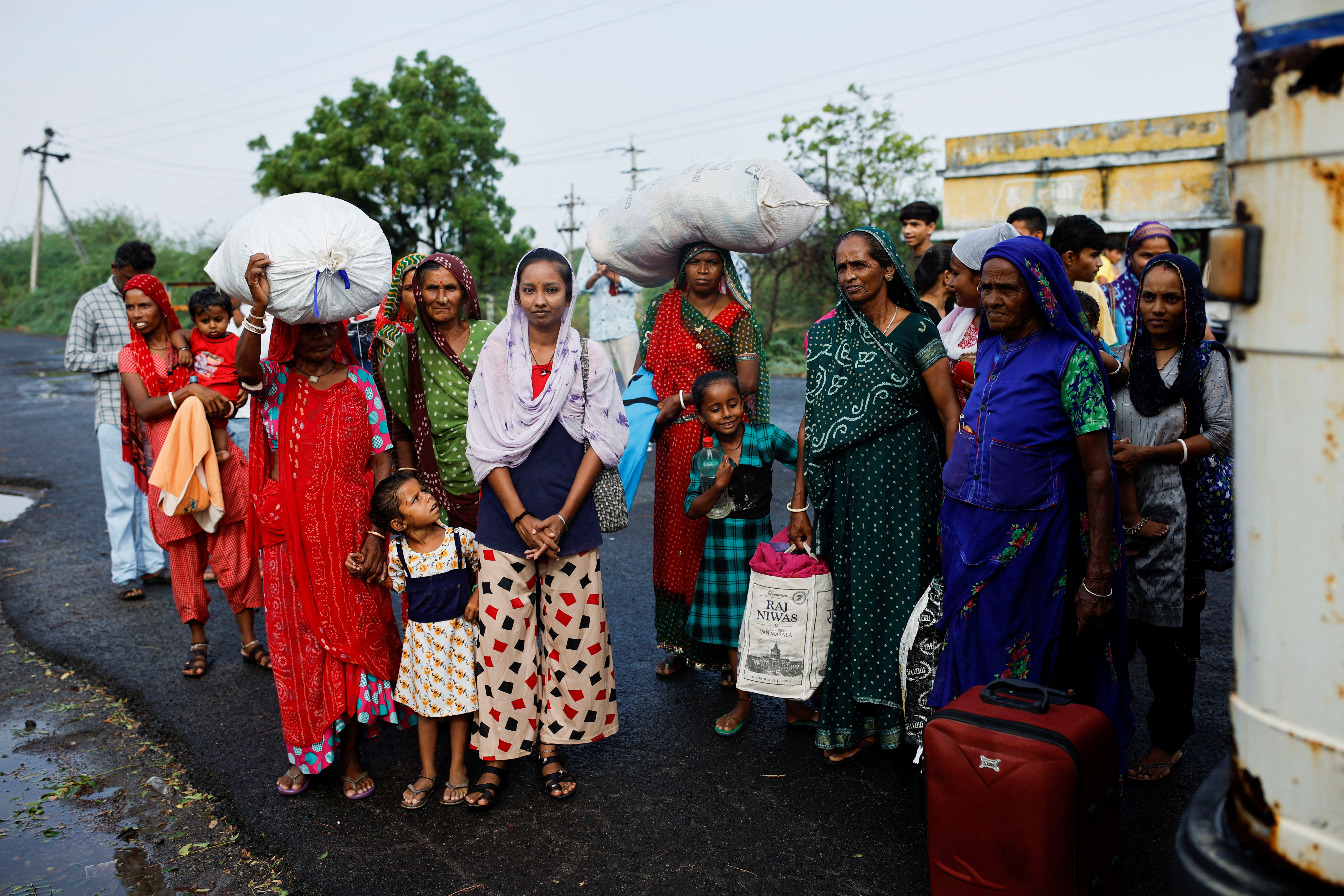 People wait to board a bus during an evacuation before the arrival of cyclone Biparjoy in Jakhau, in the western state of Gujarat, India, June 14, 2023.