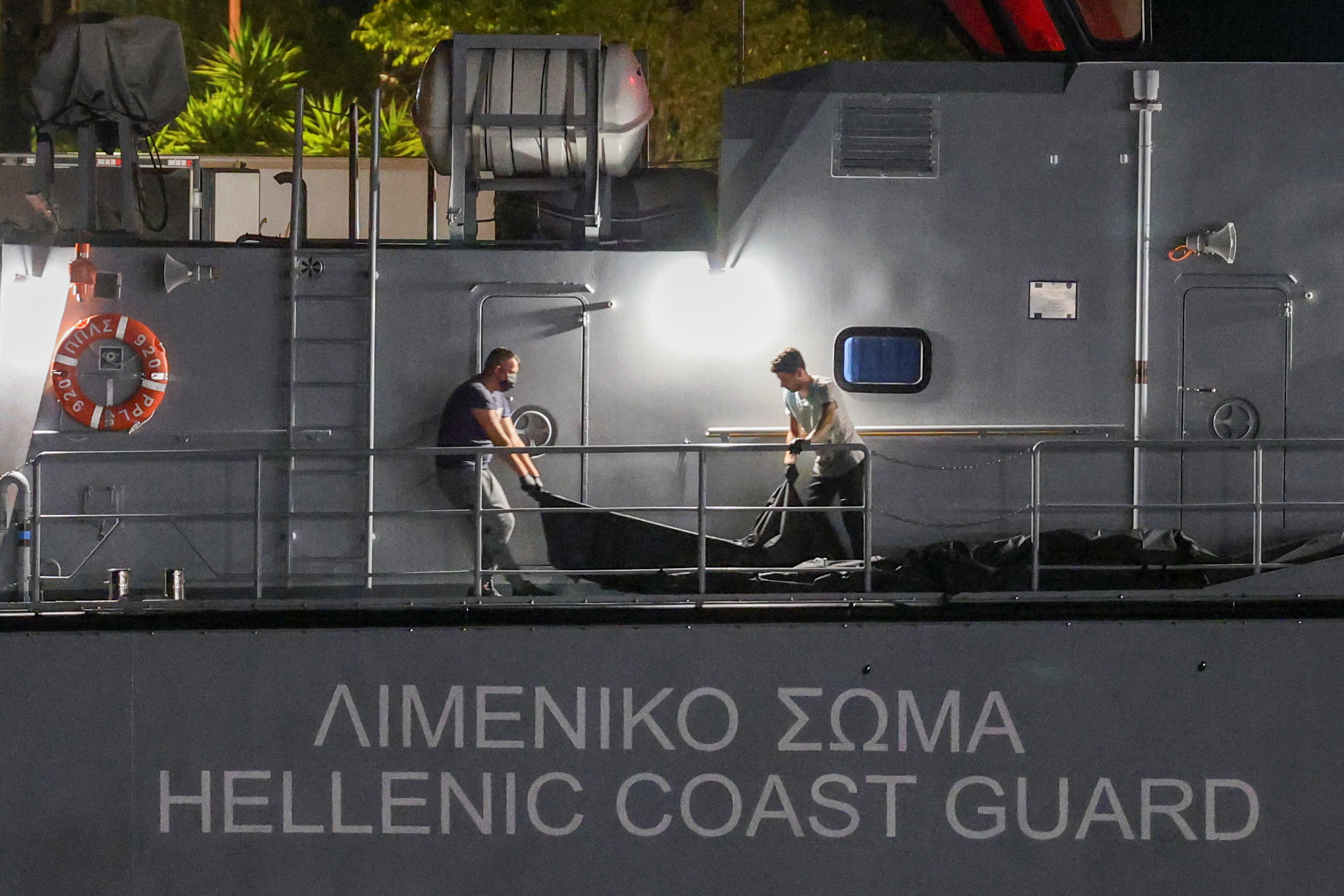 Men transfer body bags carrying migrants who died after their boat capsized in the open sea off Greece, onboard a Hellenic Coast Guard vessel at the port of Kalamata, Greece, June 14, 2023. REUTERS/Stelios Misinas
