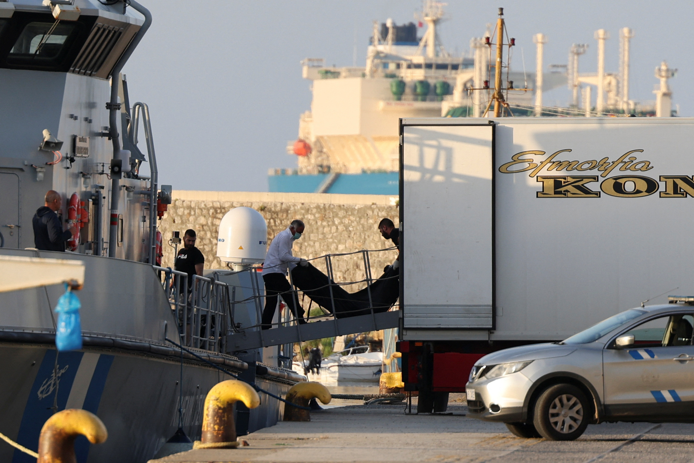Men transfer body bags carrying migrants who died after their boat capsized