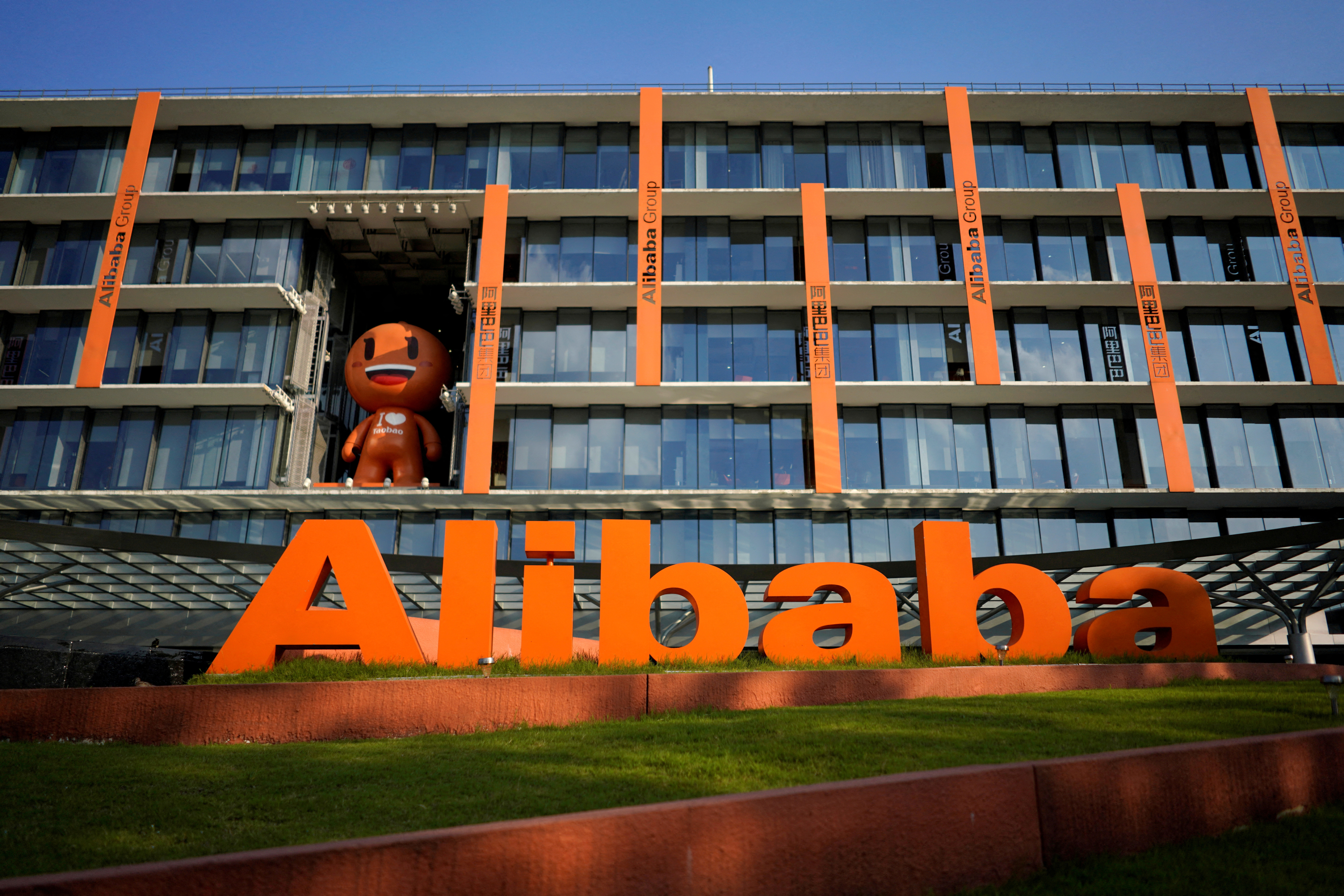A view of the Alibaba HQ. It's a glass building with orange decoration. The company logo - in orange - is in front.