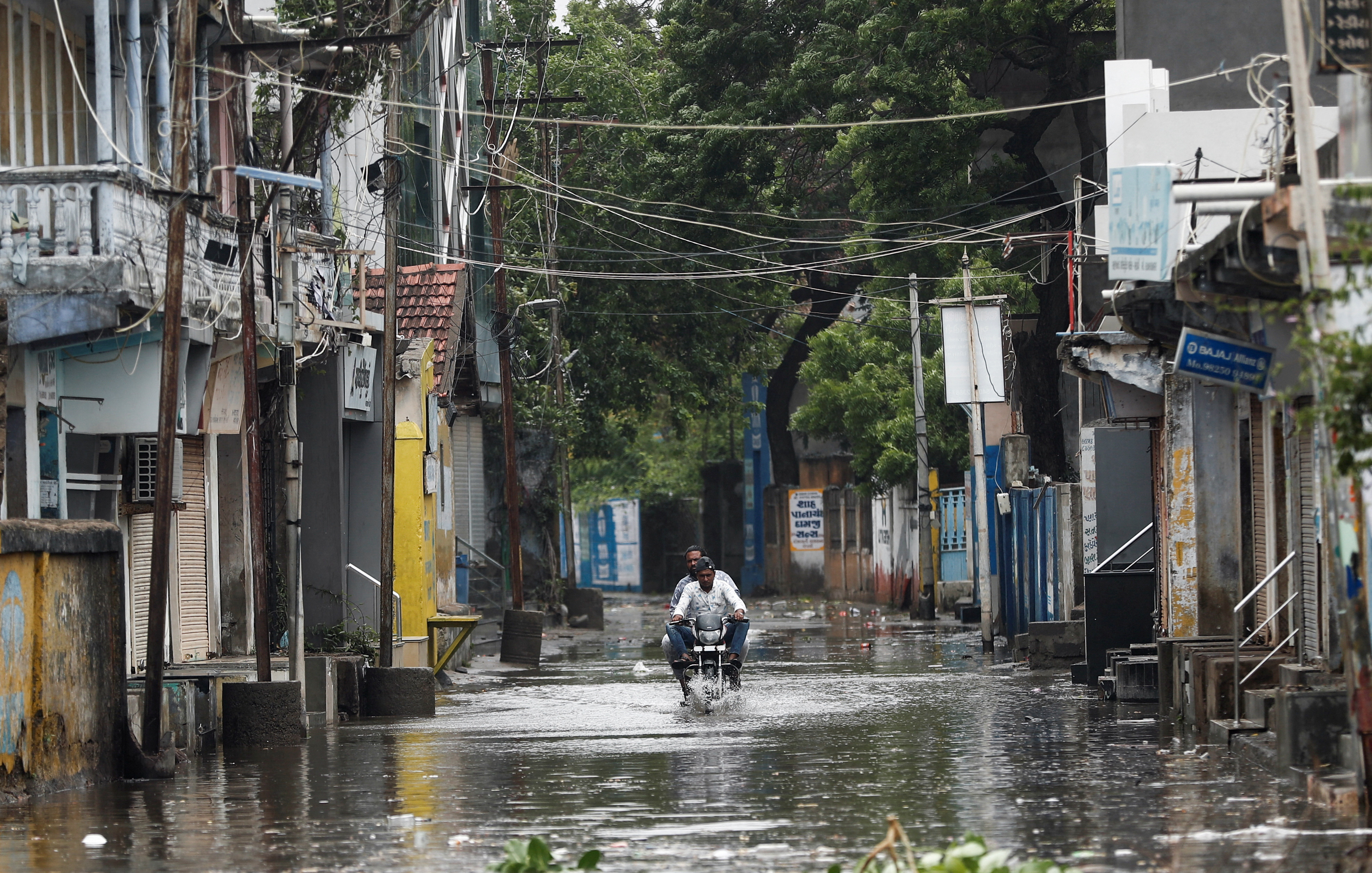 man rides a motorcycle through a waterlogged street in Mandvi before the arrival of cyclone Biparjoy in the western state of Gujarat, India, June 15, 2023. REUTERS/Francis Mascarenhas