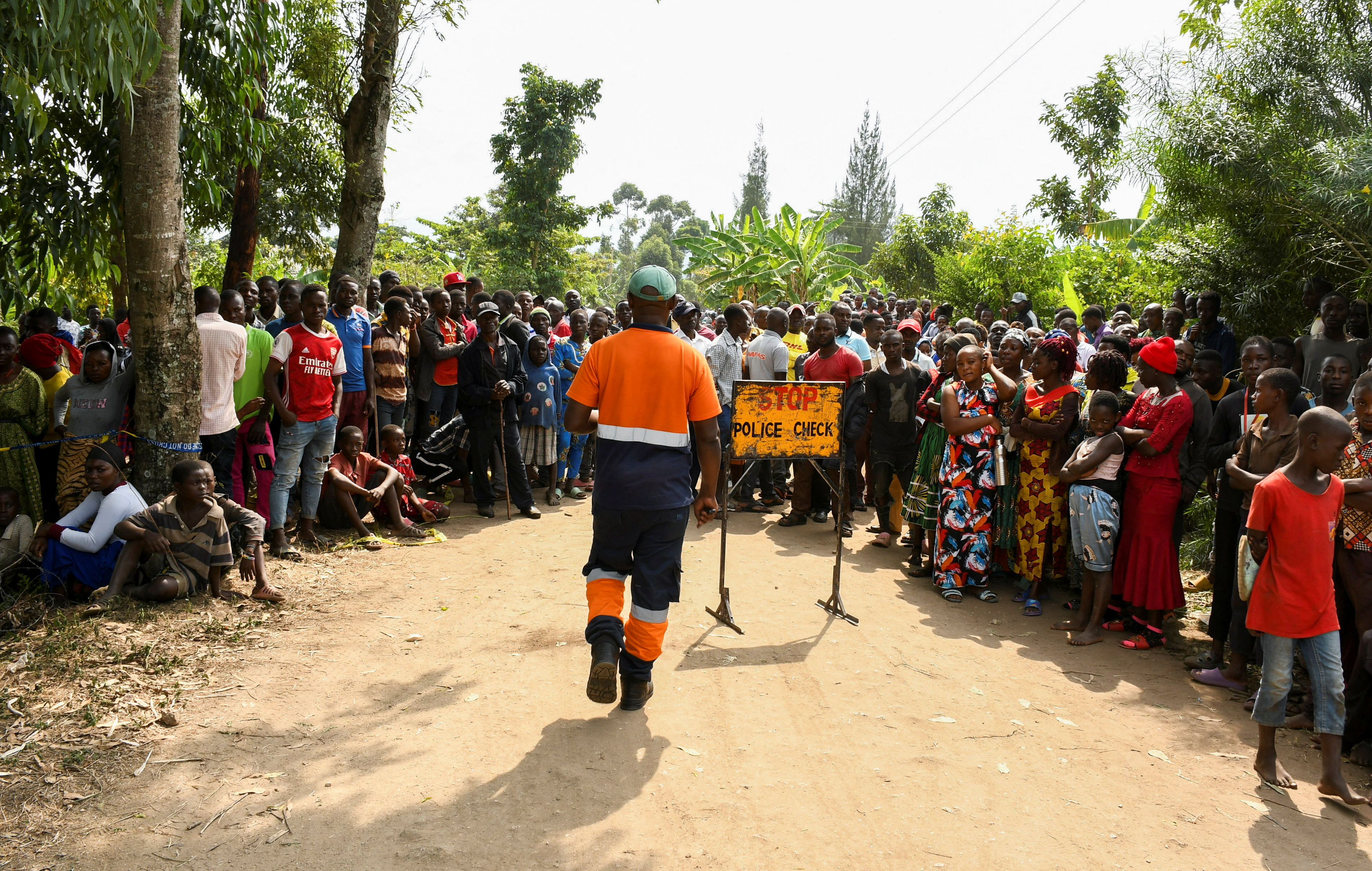 Locals gather at the cordoned scene outside the Mpondwe Lhubirira Secondary School in Mpondwe, Uganda