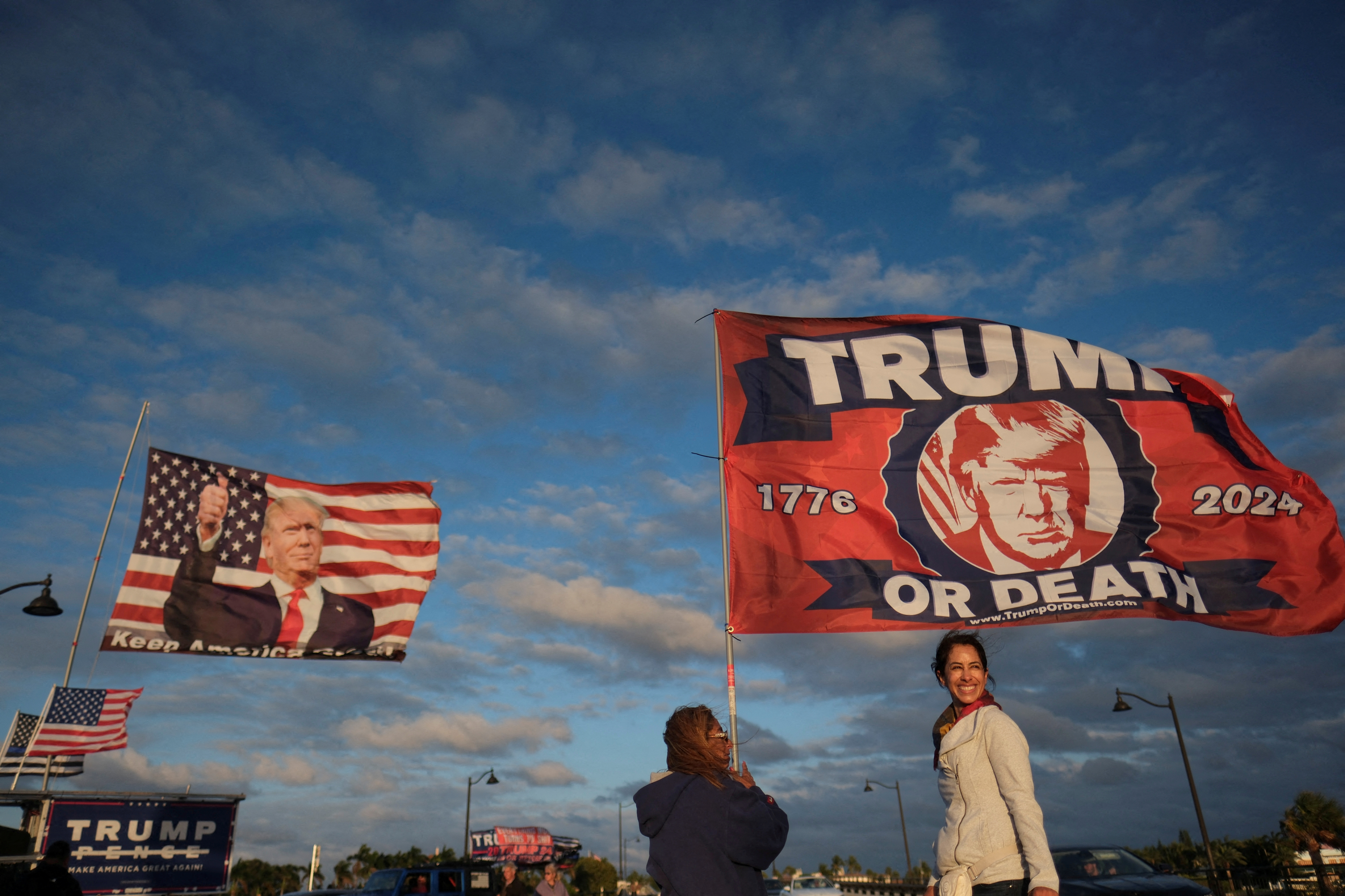 A few supporters wave flags with Trump's picture on them