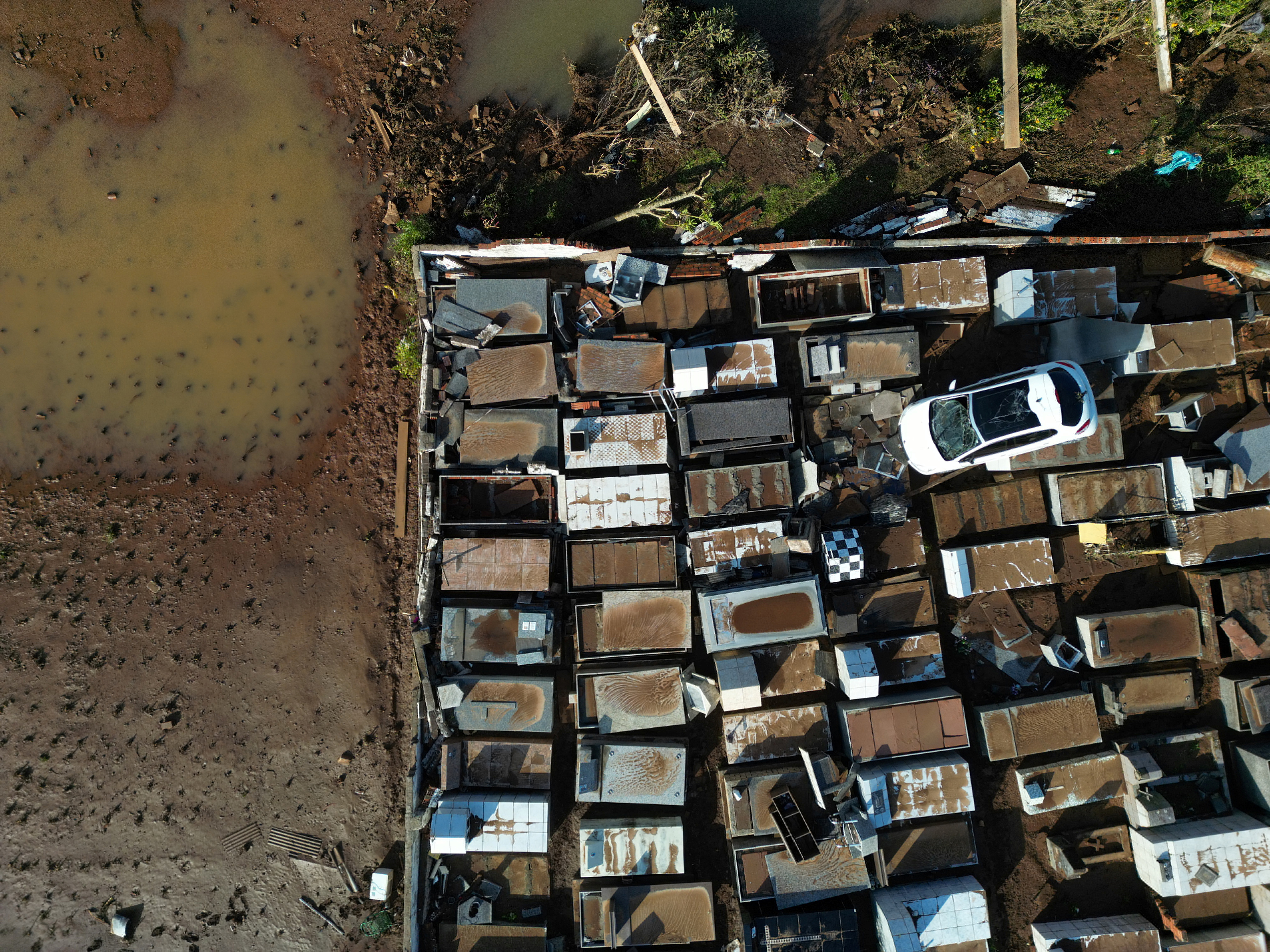 An aerial view shows a car which came to rest on top of graves at the Pedro Freiberger cemetery as a result of flooding due to heavy rains following an extratropical cyclone, in Caraa