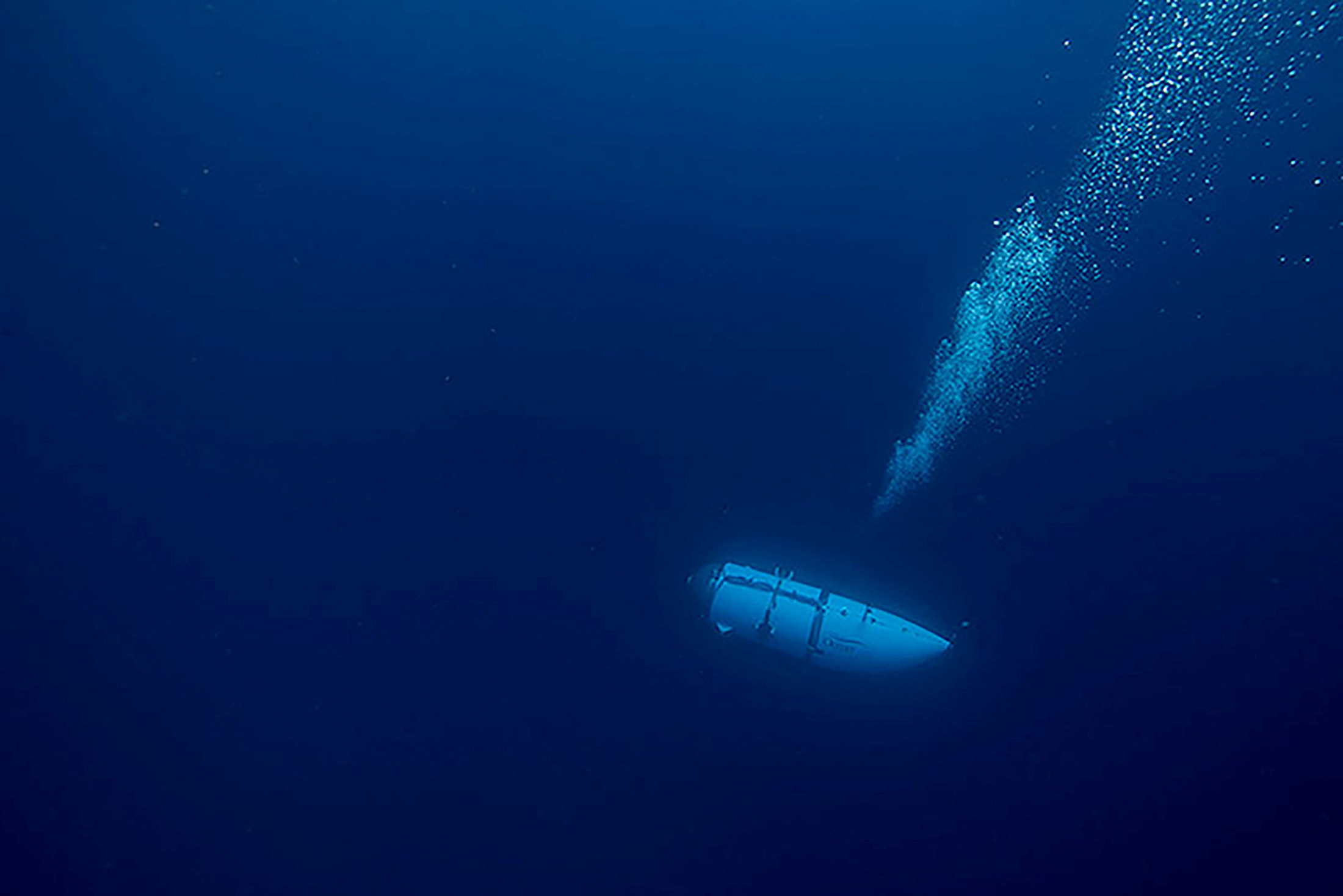 The Titan submersible, operated by OceanGate Expeditions, is seen traveling through water, a trail of bubbles behind it