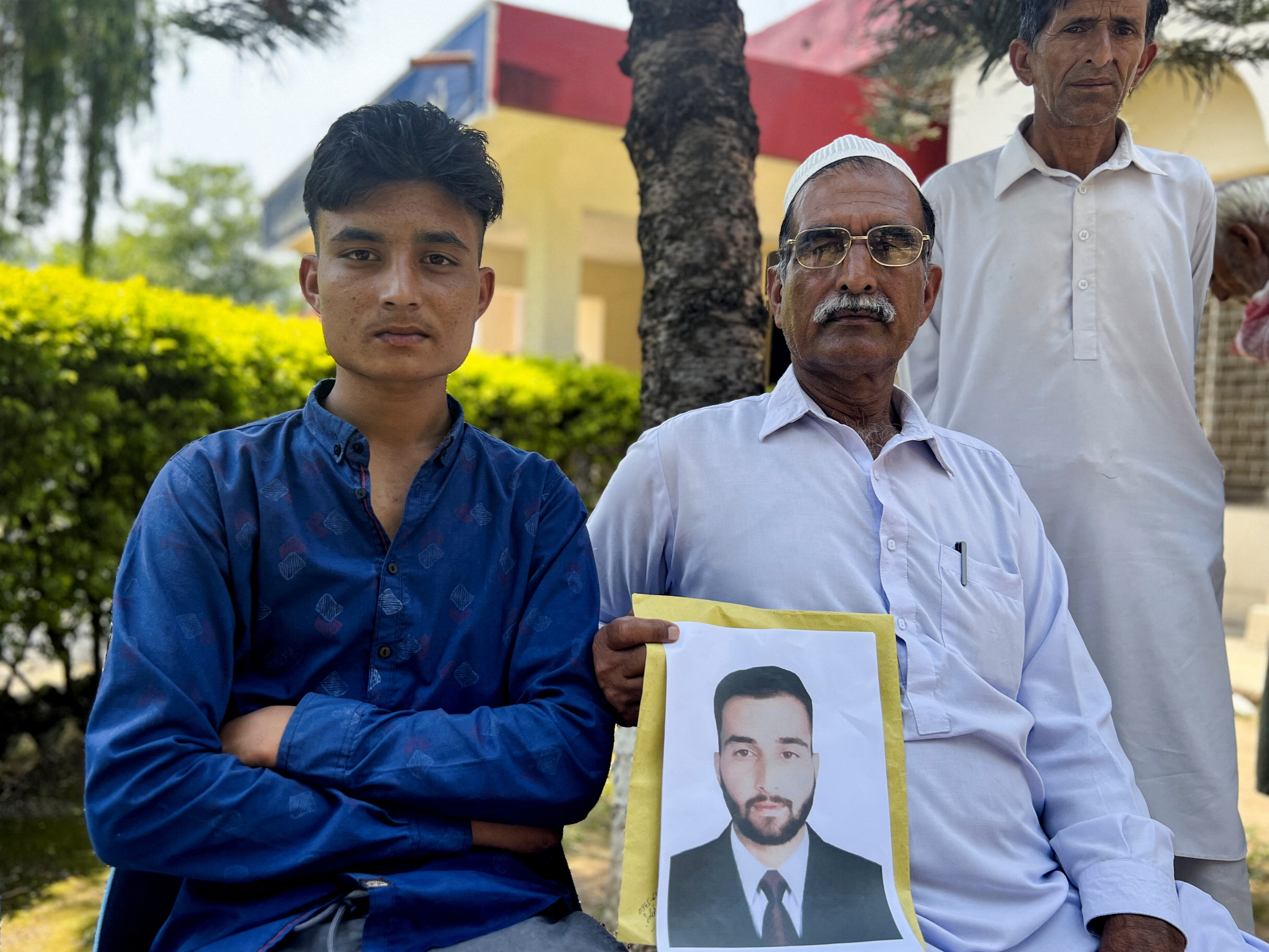 Raja Mohammad Aslam, 55, holds a photo of his son Sajid Aslam, 26, who is missing, along with others, after a migrant boat sunk off the coast of Greece,