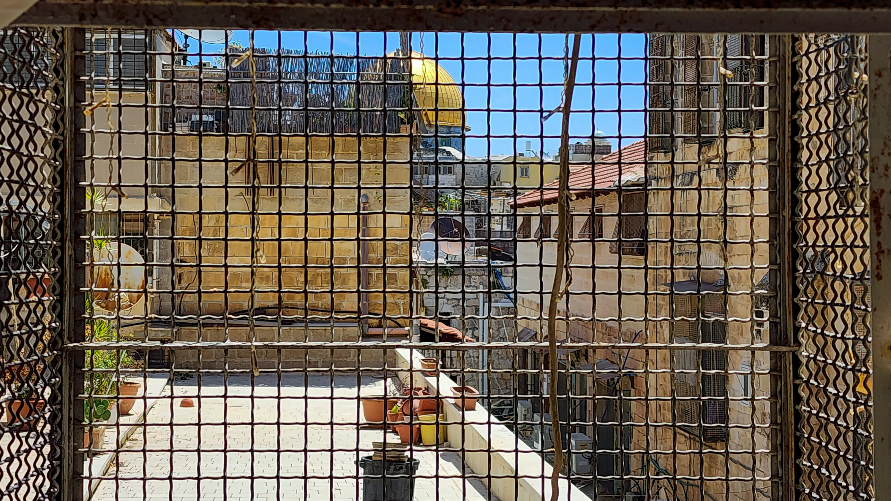 hidden view of the dome of the rock behind a barbed wire fence