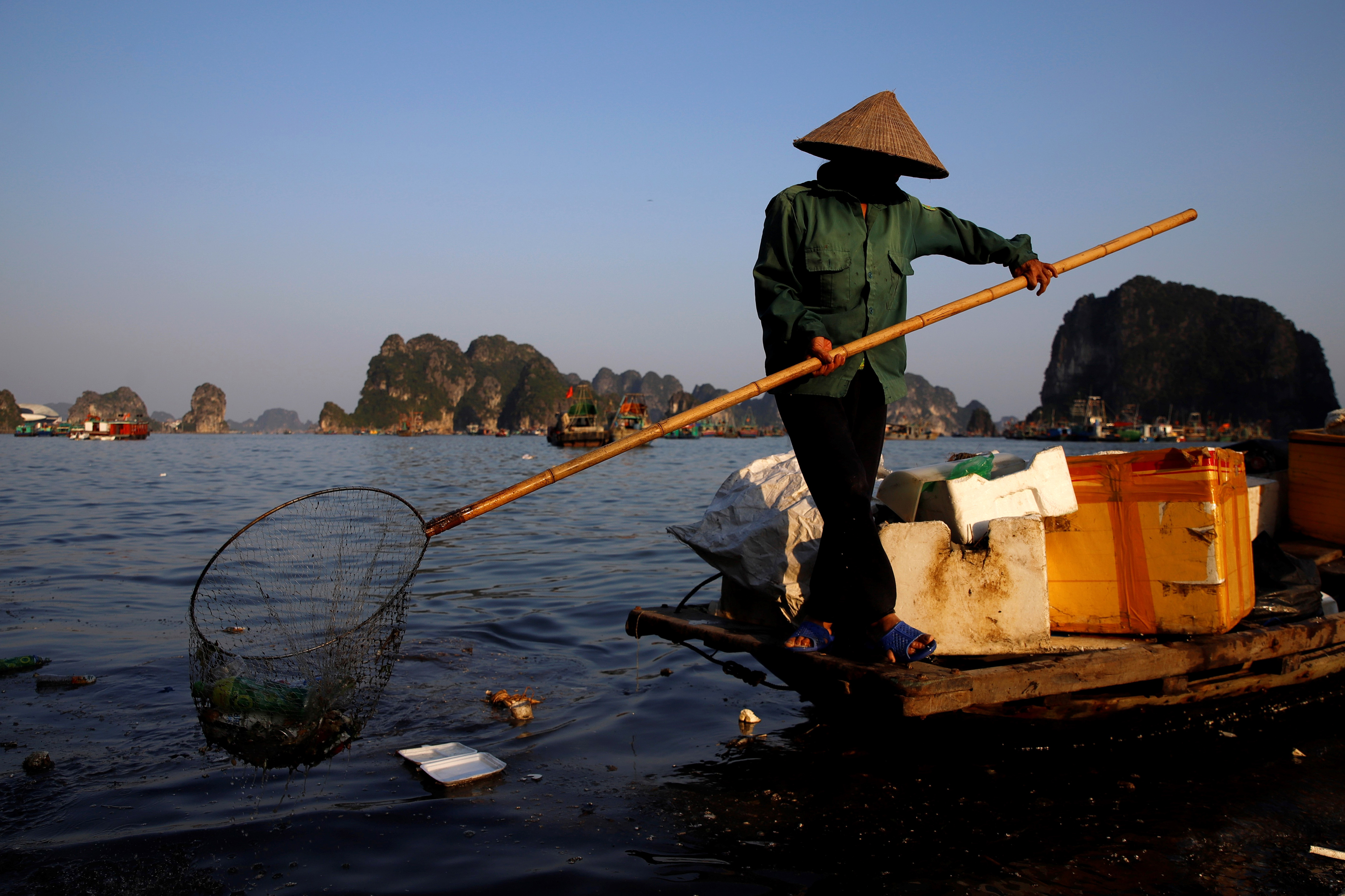a worker picks up trash from Ha Long Bay in northeast Vietnam.