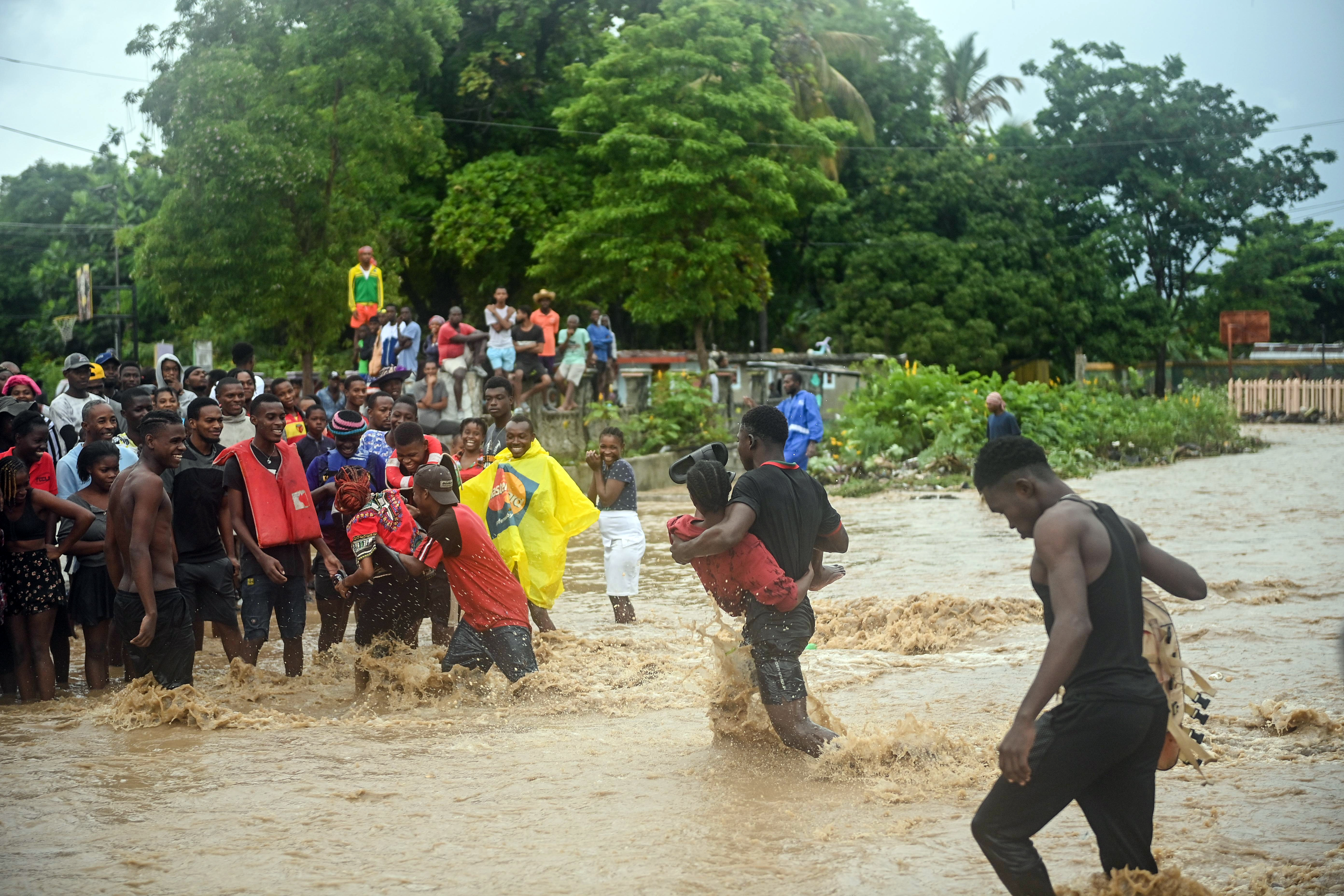 Resident wade through flooded roads in neighborhoods of Petit-Goâve, Haiti