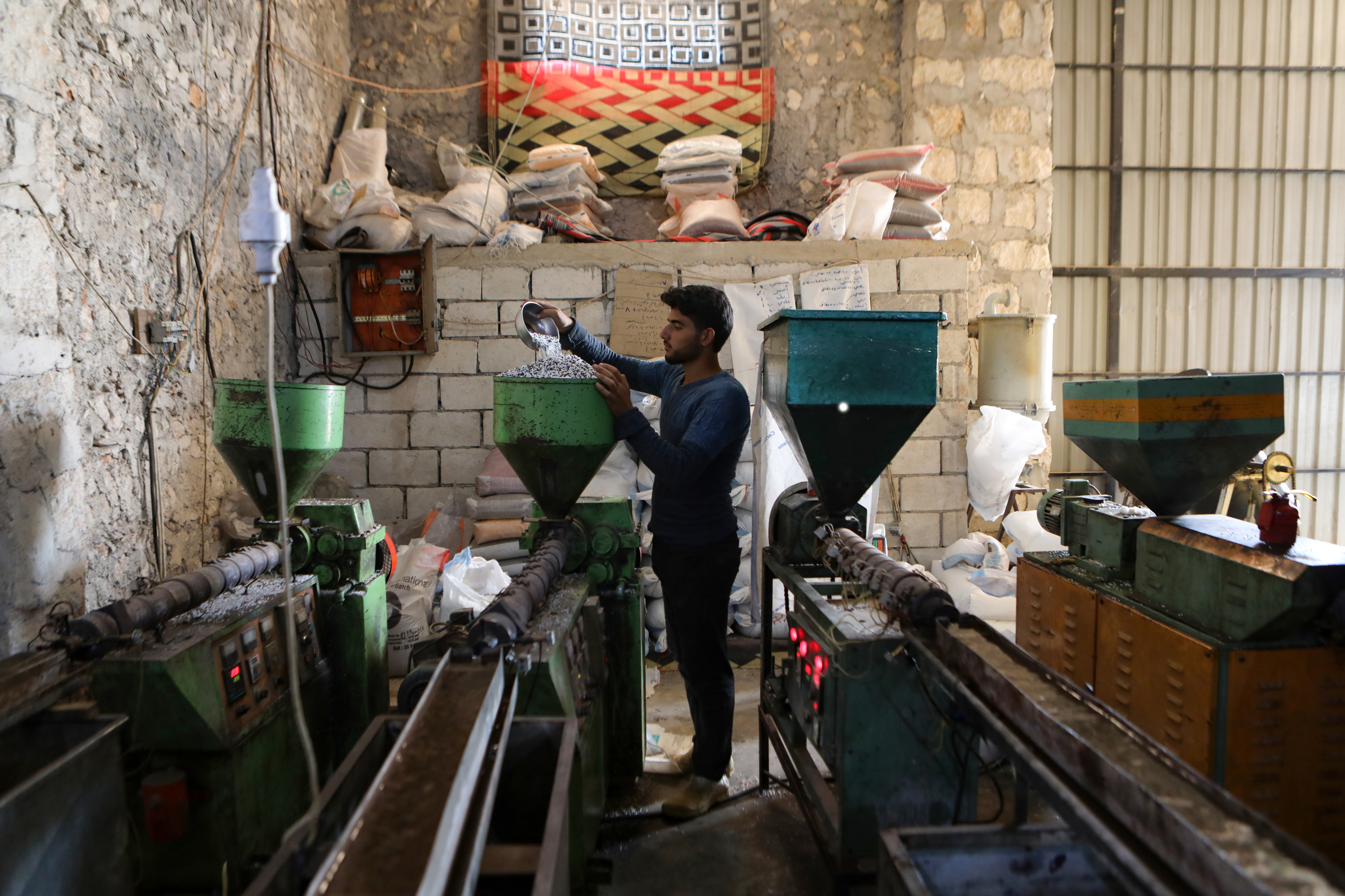 a worker feeds crushed plastic junk into a machine