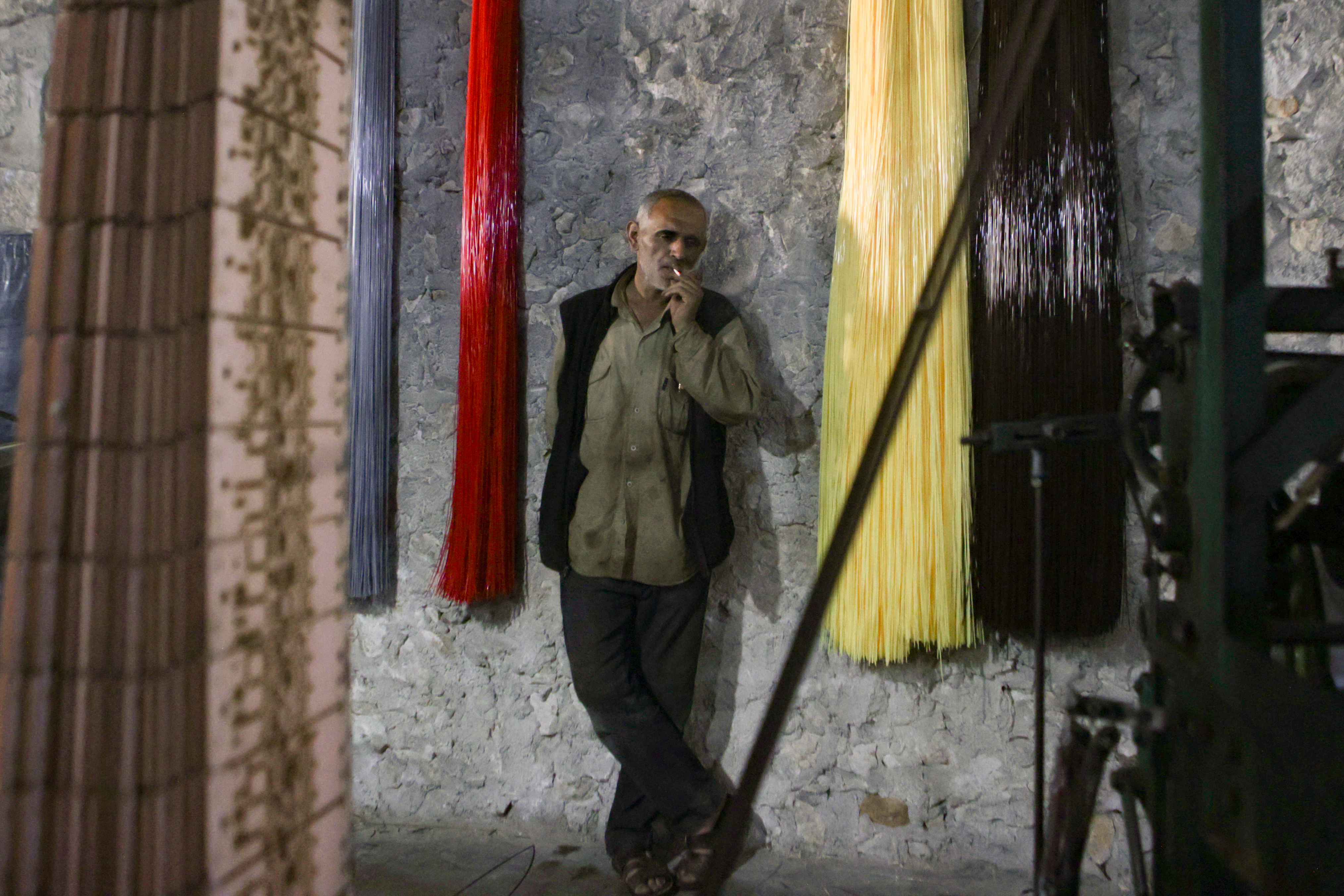 In this picture taken on June 1, 2023, a worker at a factory making mats and rugs from recycled plastic, takes a break in Sarmada in Syria's northwestern Idlib province.