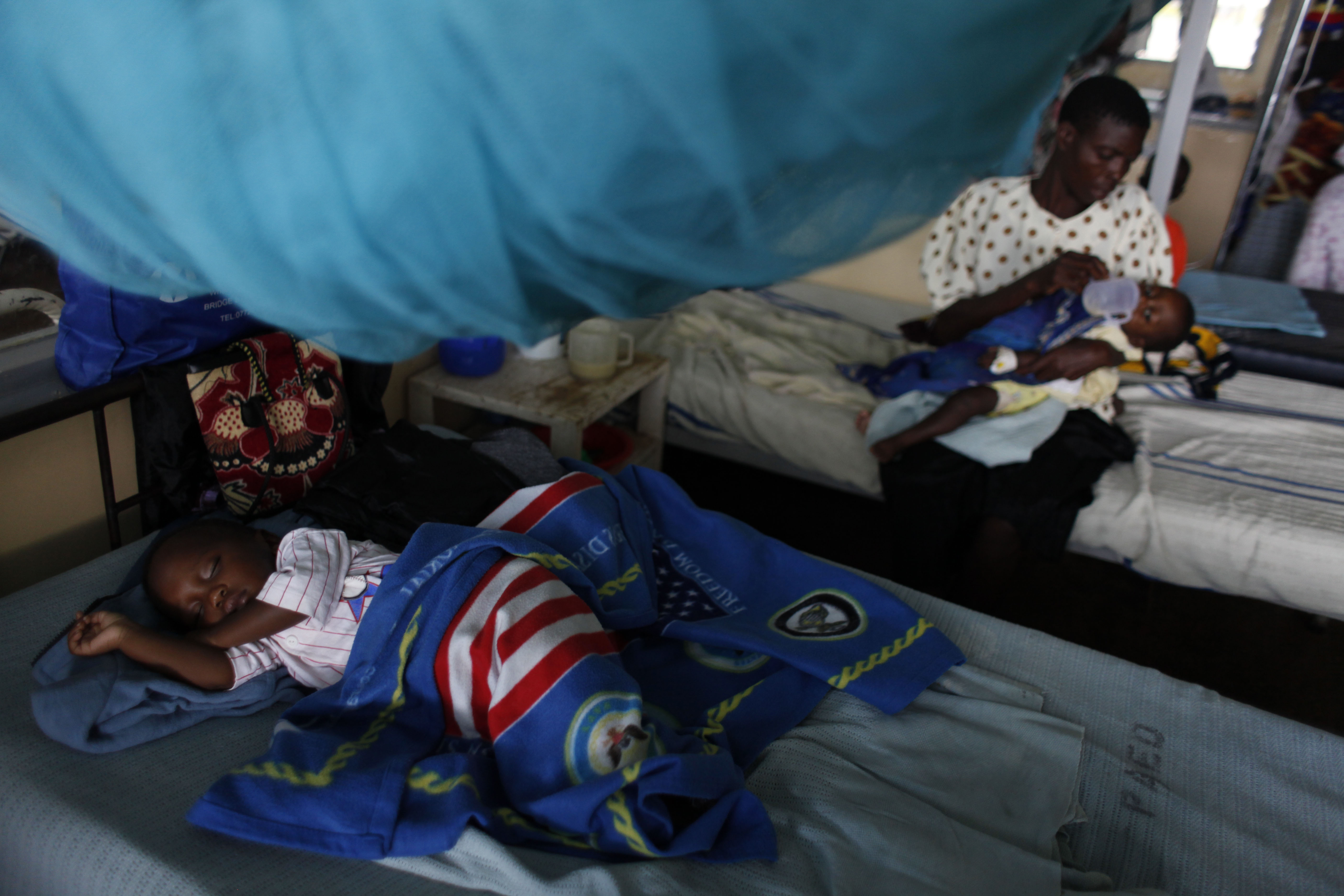 A child suffering from malaria sleeps under a mosquito net