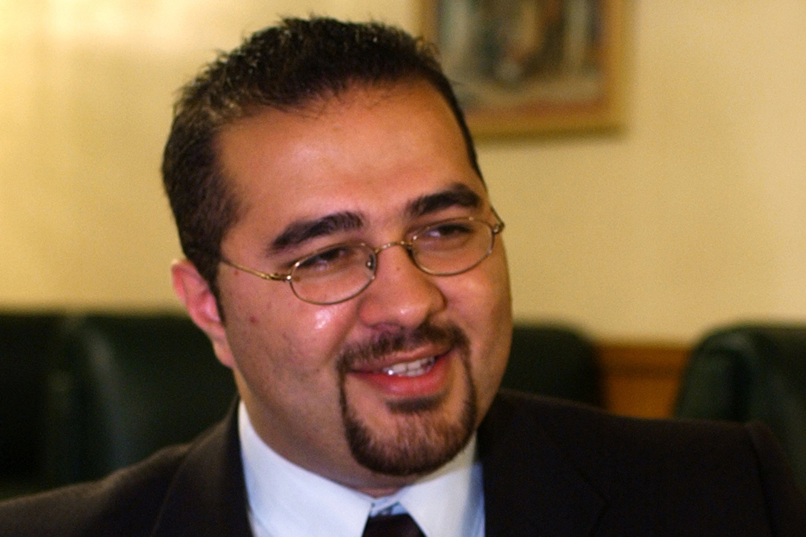 A close-up of a man with a goatee in a suit and tie.