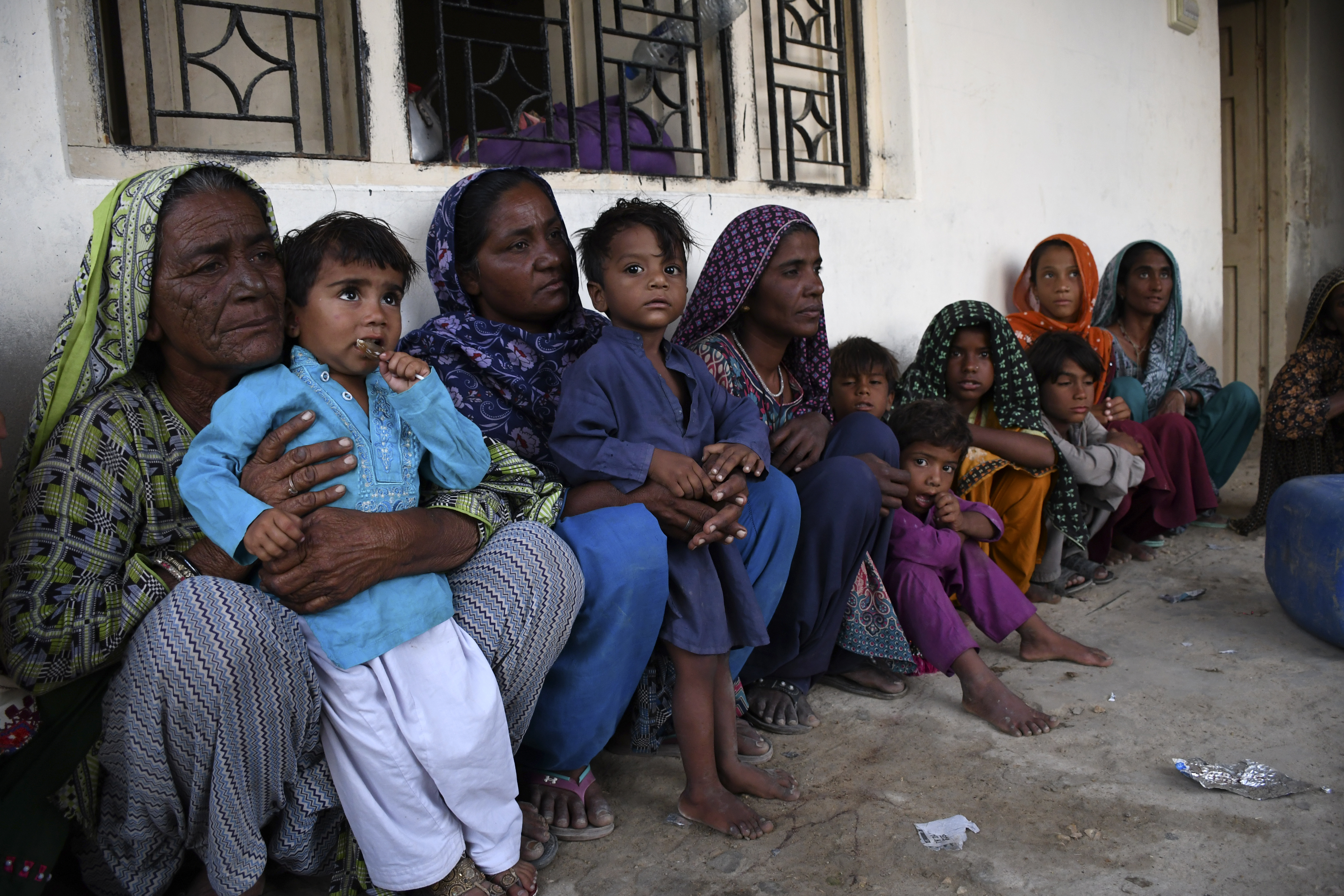 Women and children take shelter in a school building after fleeing from their villages due to Cyclone Biparjoy approaching, at a costal area of Badin district,