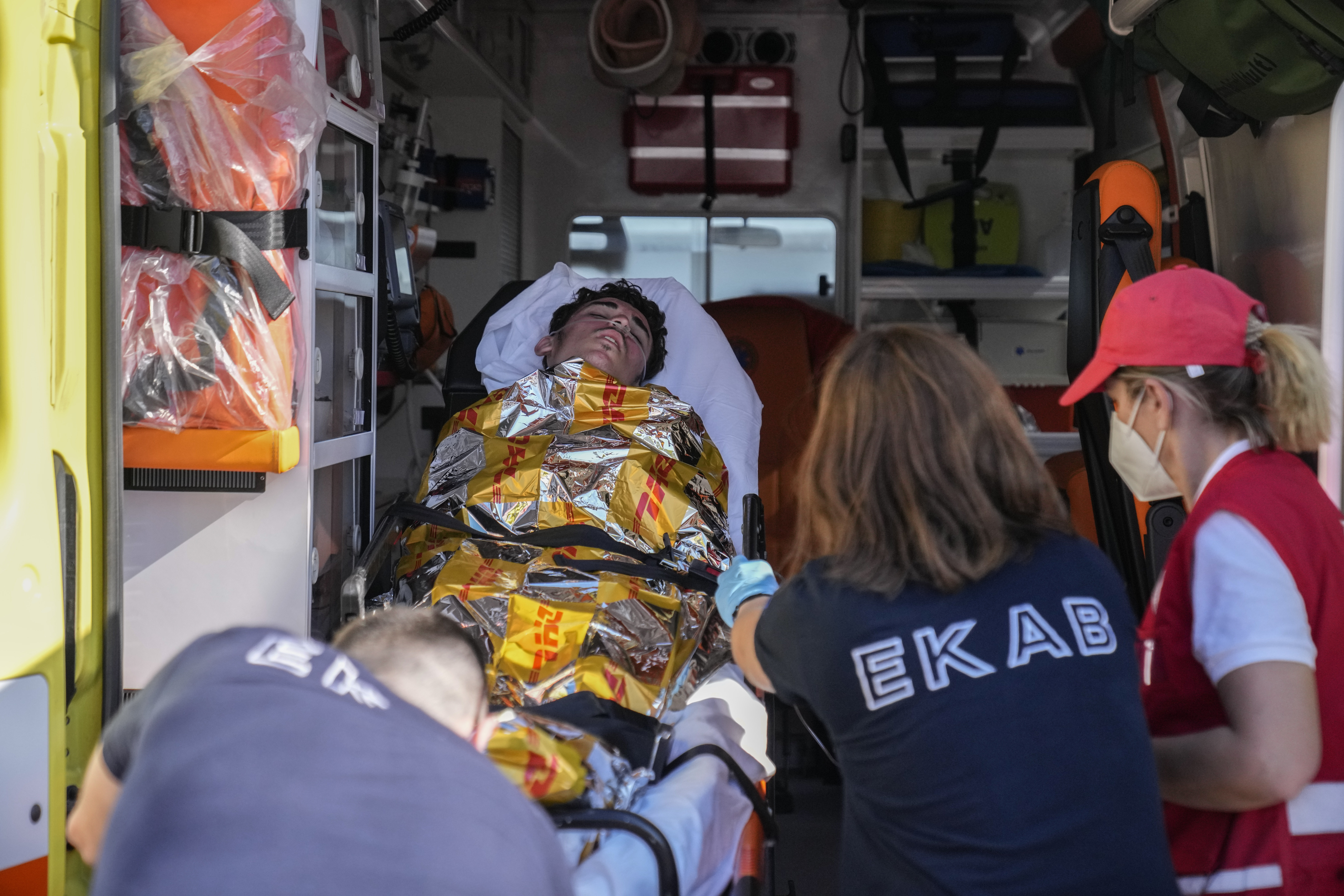 Paramedics carry an injured survivor of a shipwreck to an ambulance at the port in Kalamata town