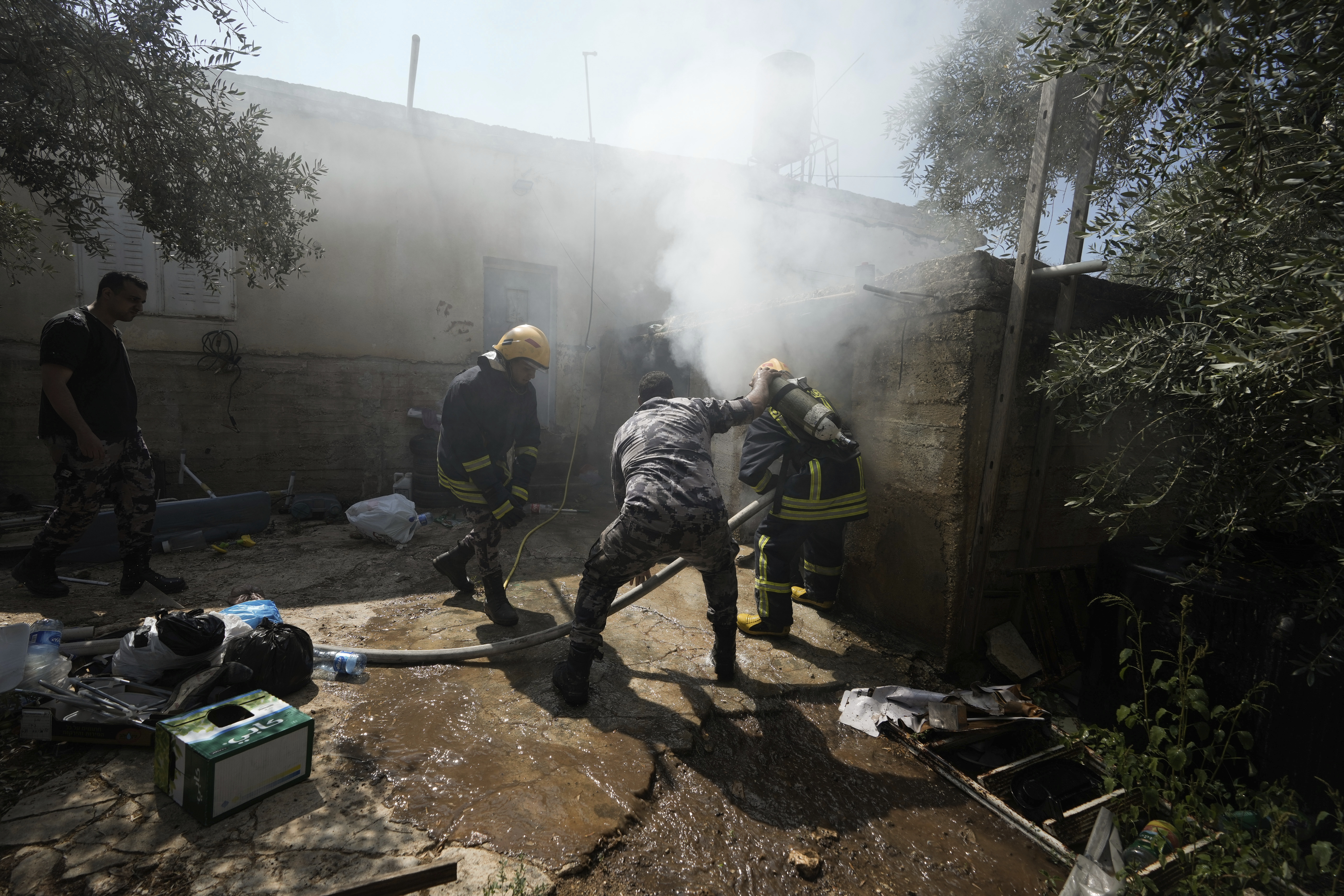 Palestinian firefighters try to extinguish a fire set by Jewish settlers in the West Bank town of Turmus Ayya
