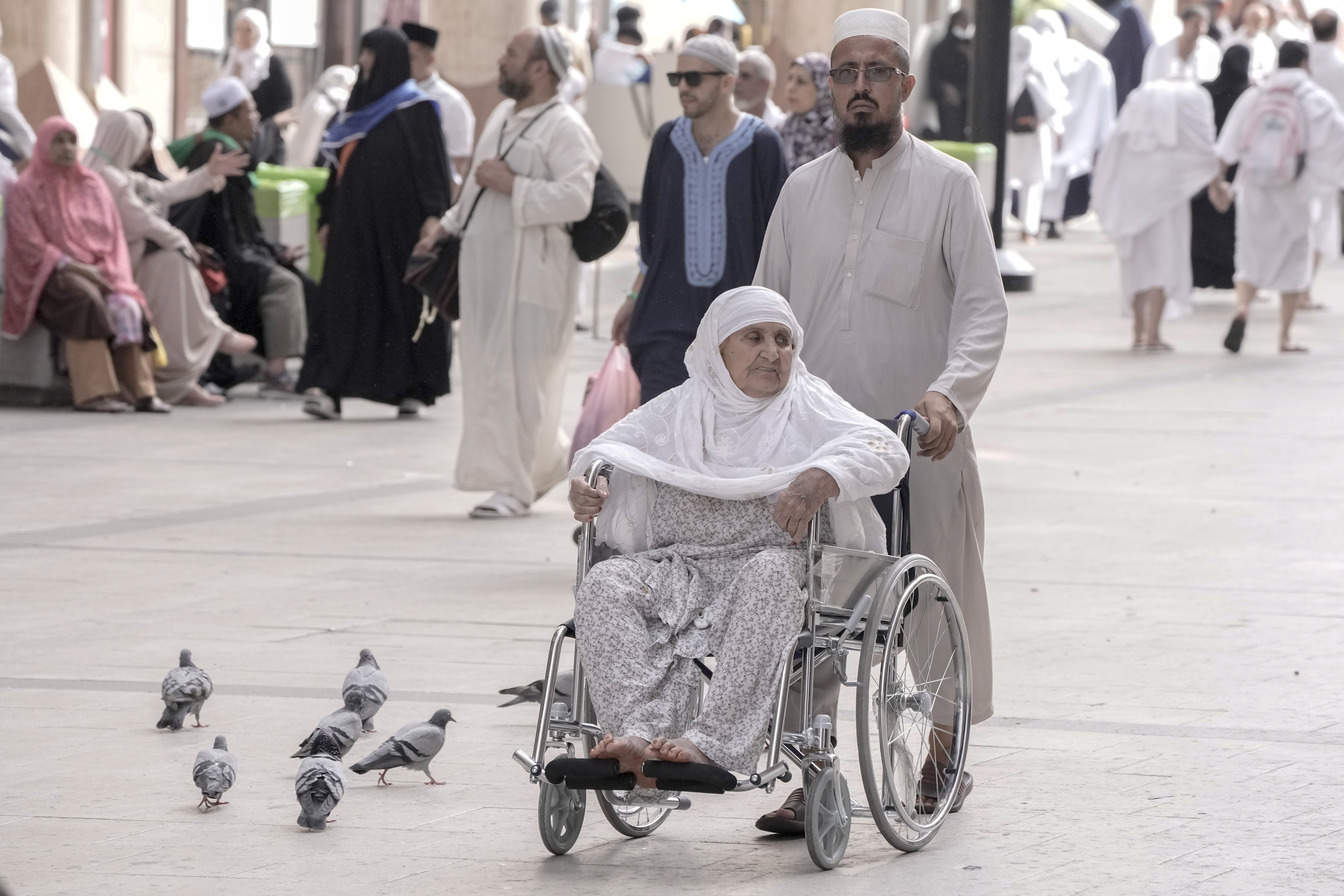 Pakistani pilgrim Gul Rehman pushes his mother on a wheel chair