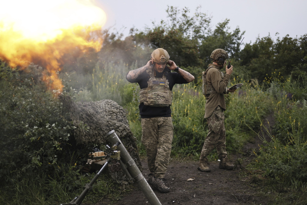 A Ukrainian servicemen of the 3rd separate assault brigade speaks on the radio while another serviceman is firing 82mm mortar towards Russian positions at the frontline near Bakhmut, Donetsk region, Ukraine, Thursday, June 29, 2023. (AP Photo/Alex Babenko)