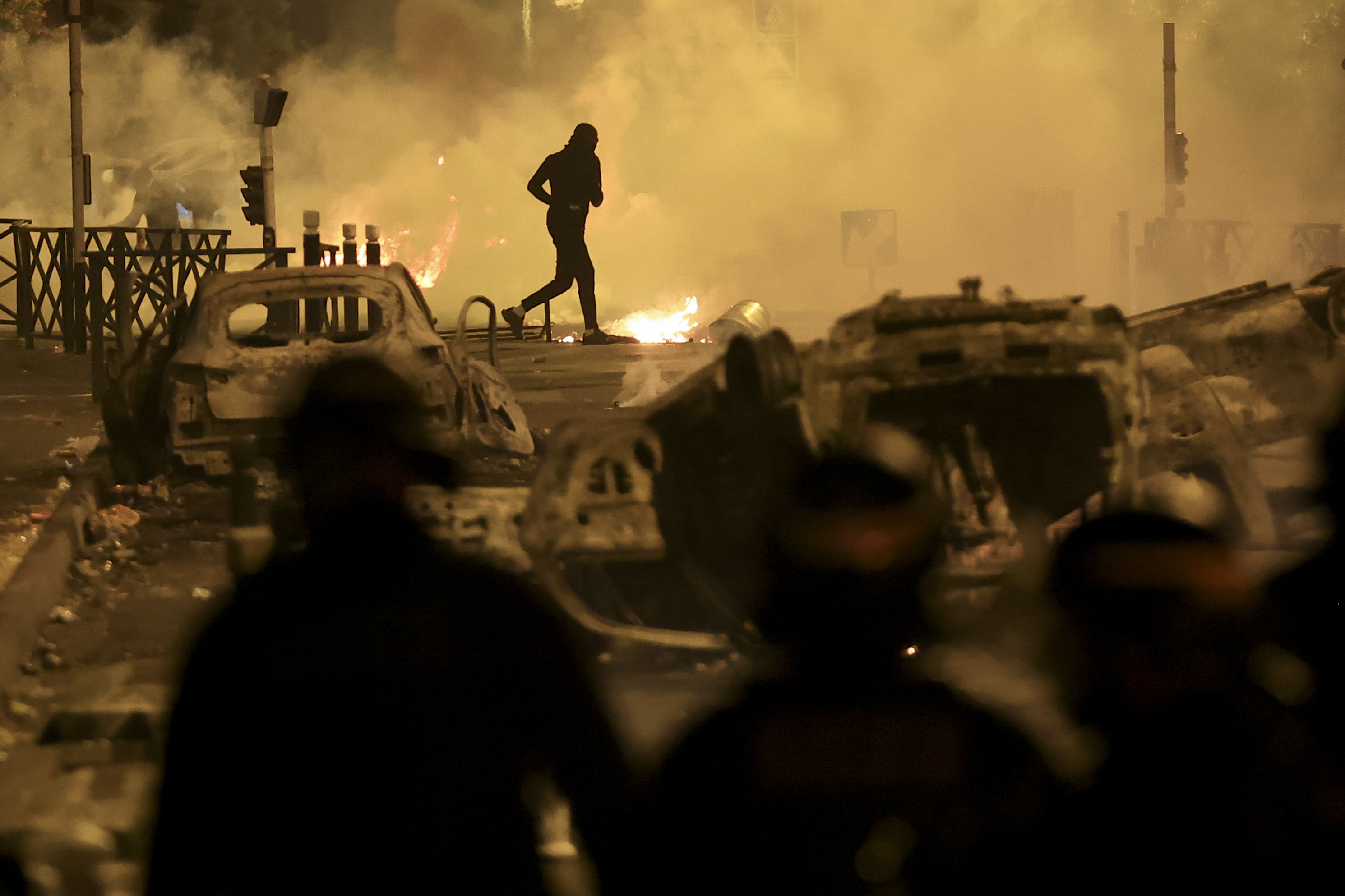 A demonstrator runs on the third night of protests sparked by the fatal police shooting of a 17-year-old driver in the Paris suburb of Nanterre, France, Friday, June 30, 2023. The June 27 shooting of the teen, identified as Nahel, triggered urban violence and stirred up tensions between police and young people in housing projects and other neighborhoods. (AP Photo/Aurelien Morissard)