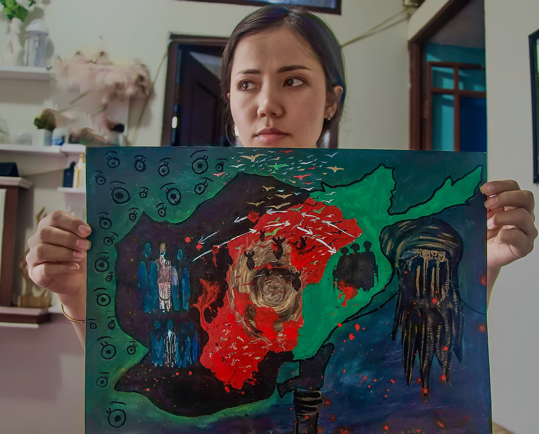 Farahnaz holding up a painting she has done. 