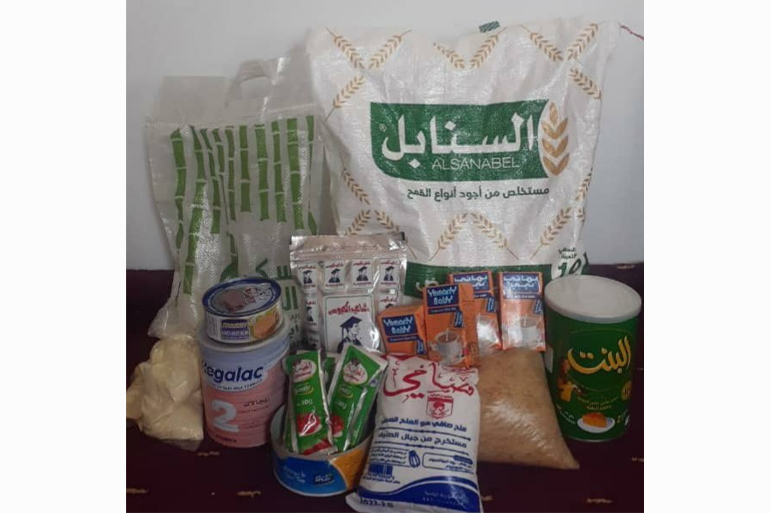 A photo of sacks and boxes of rice, sugar, tea and other things and tins of baby formula and food.
