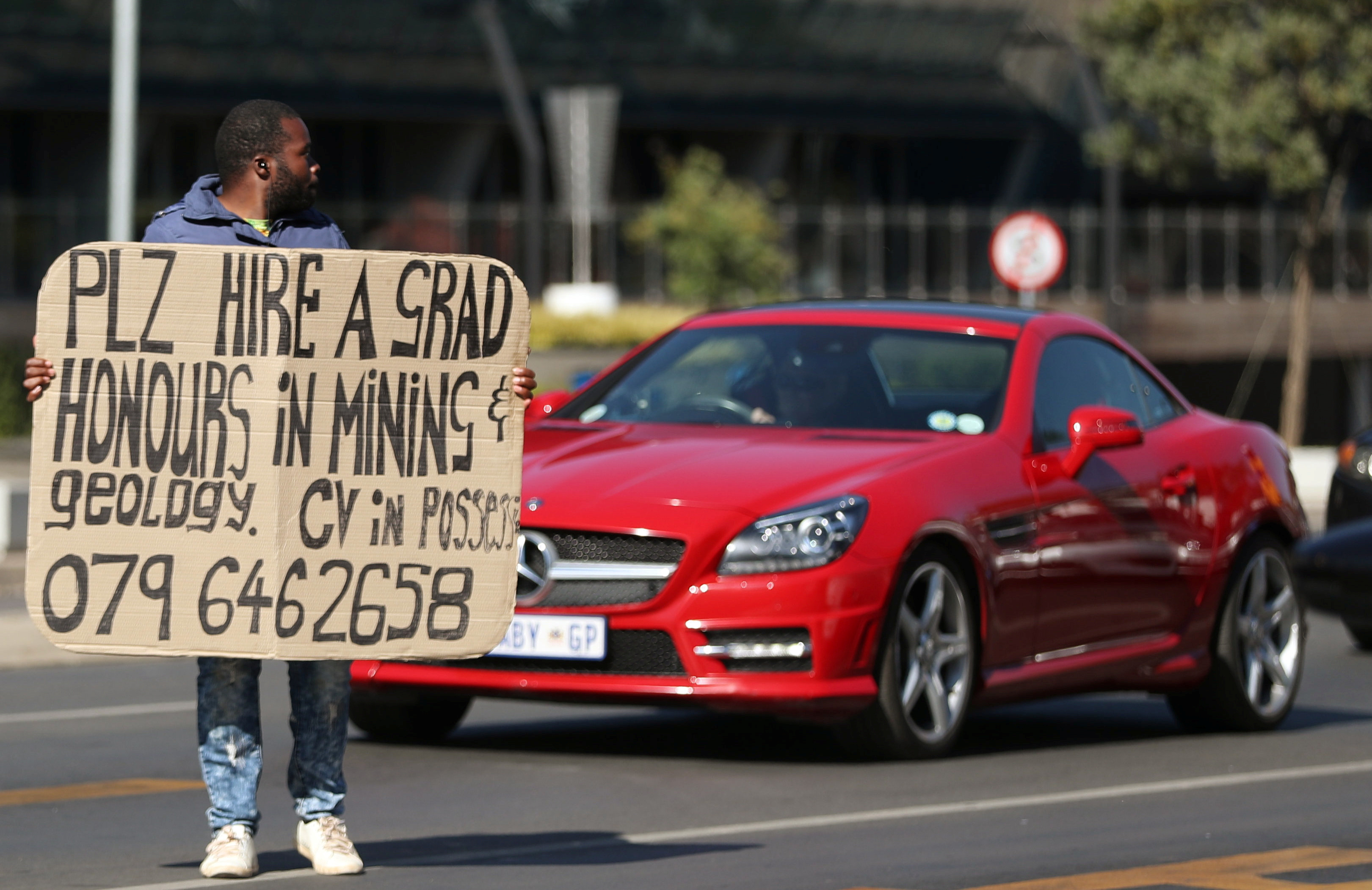 A man holds a placard looking for work in South Africa