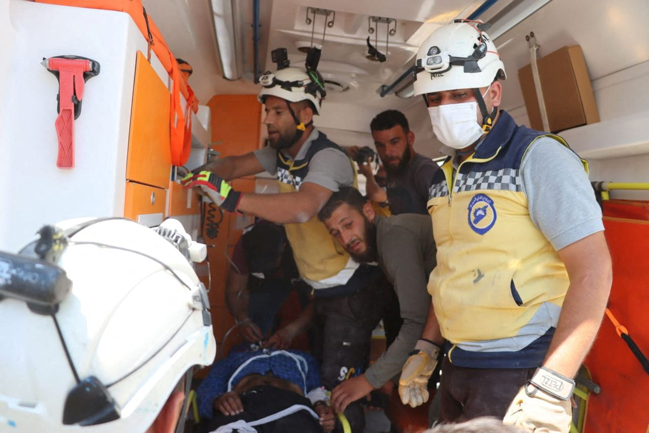 Volunteers in white helmets and yellow vests are seen in a healthcare van.