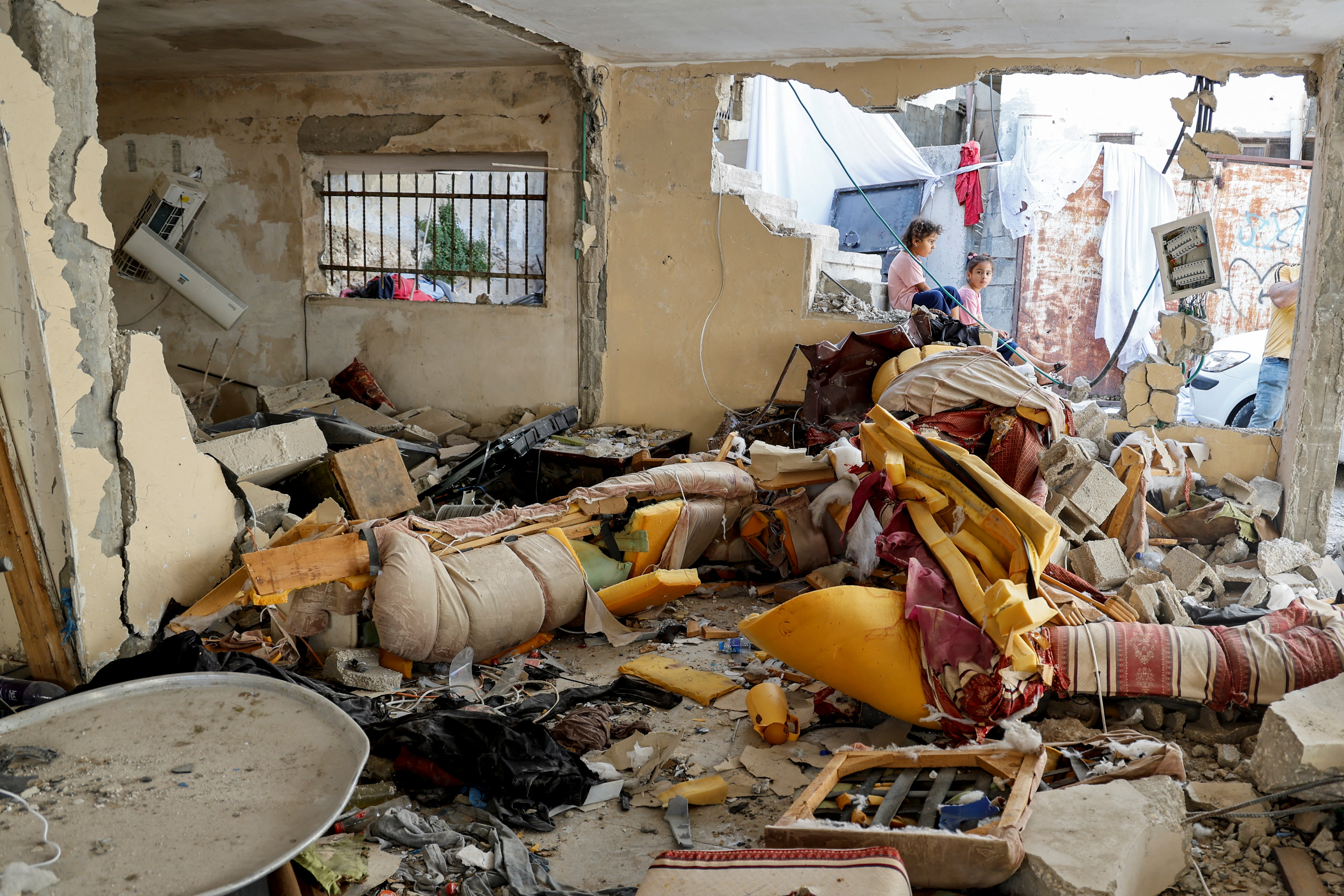 Palestinian girls sit outside a damaged house following the Israeli siege on Jenin in the occupied West Bank on July 5, 2023
