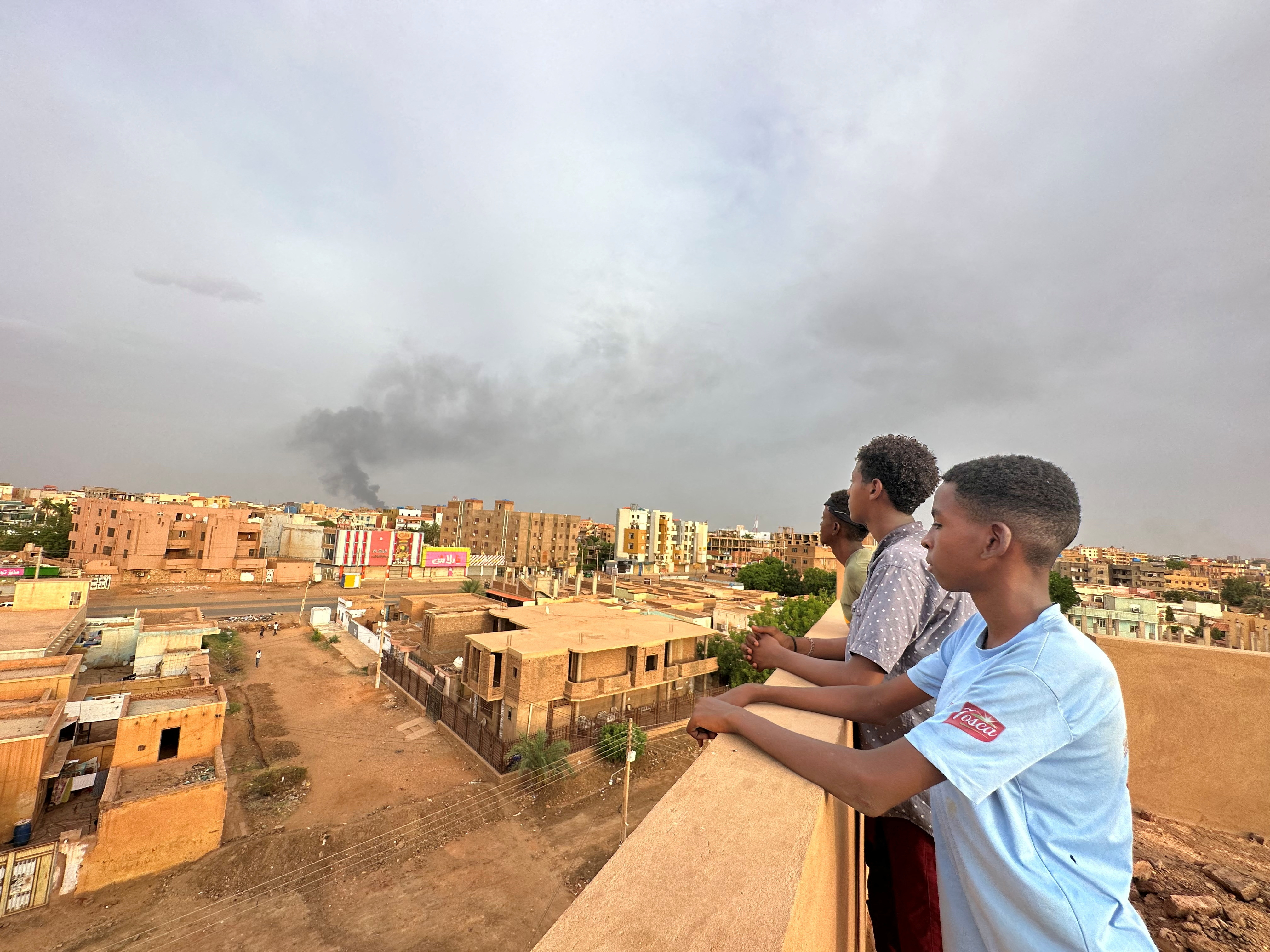 People watch as smoke rises during clashes between the army and the paramilitary Rapid Support Forces (RSF)
