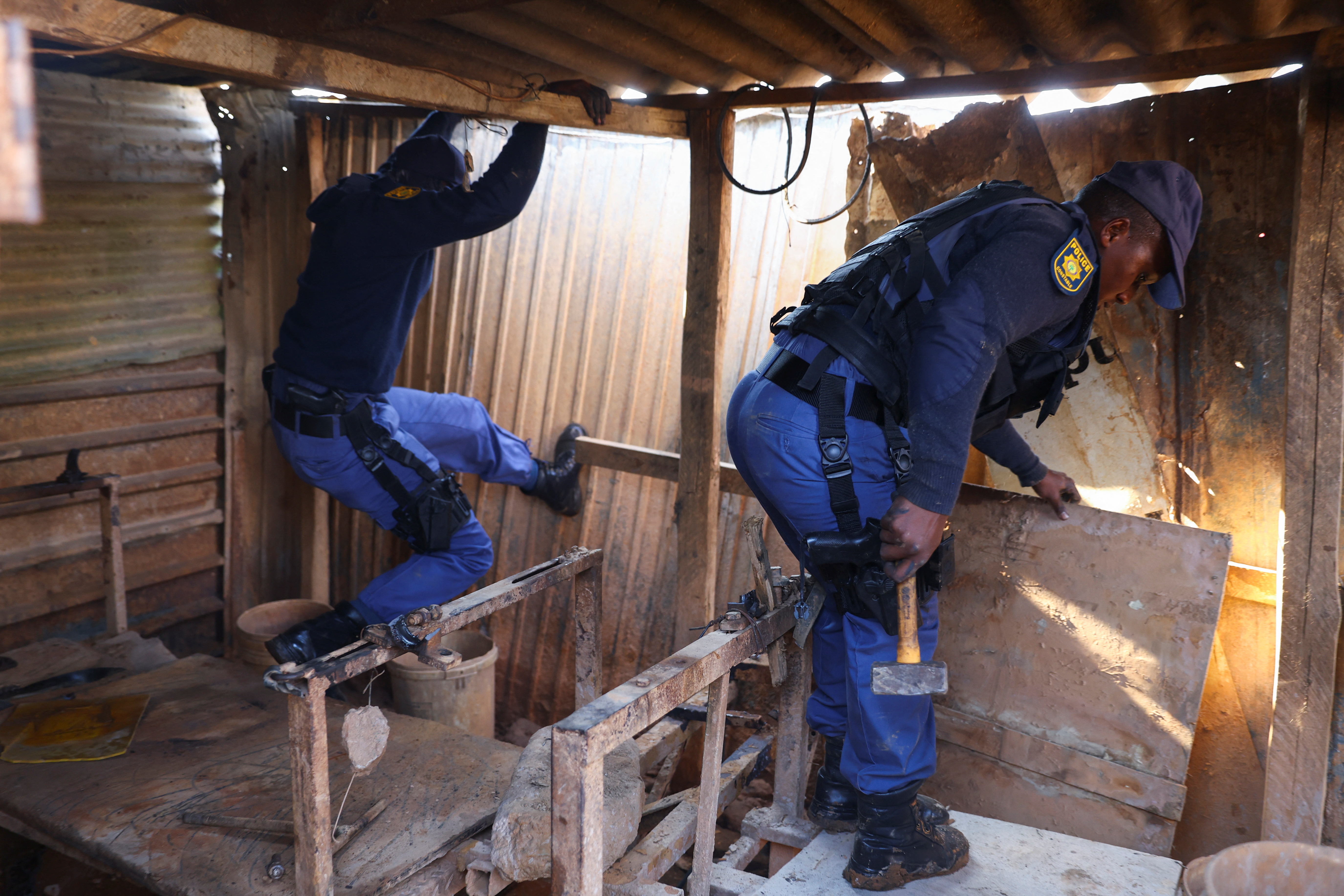 Police officers inspect the scene of a suspected gas leak linked to illegal mining, in the Angelo shack settlement, near Boksburg, east of Johannesburg, South Africa July 6, 2023 [Siphiwe Sibeko/Reuters]