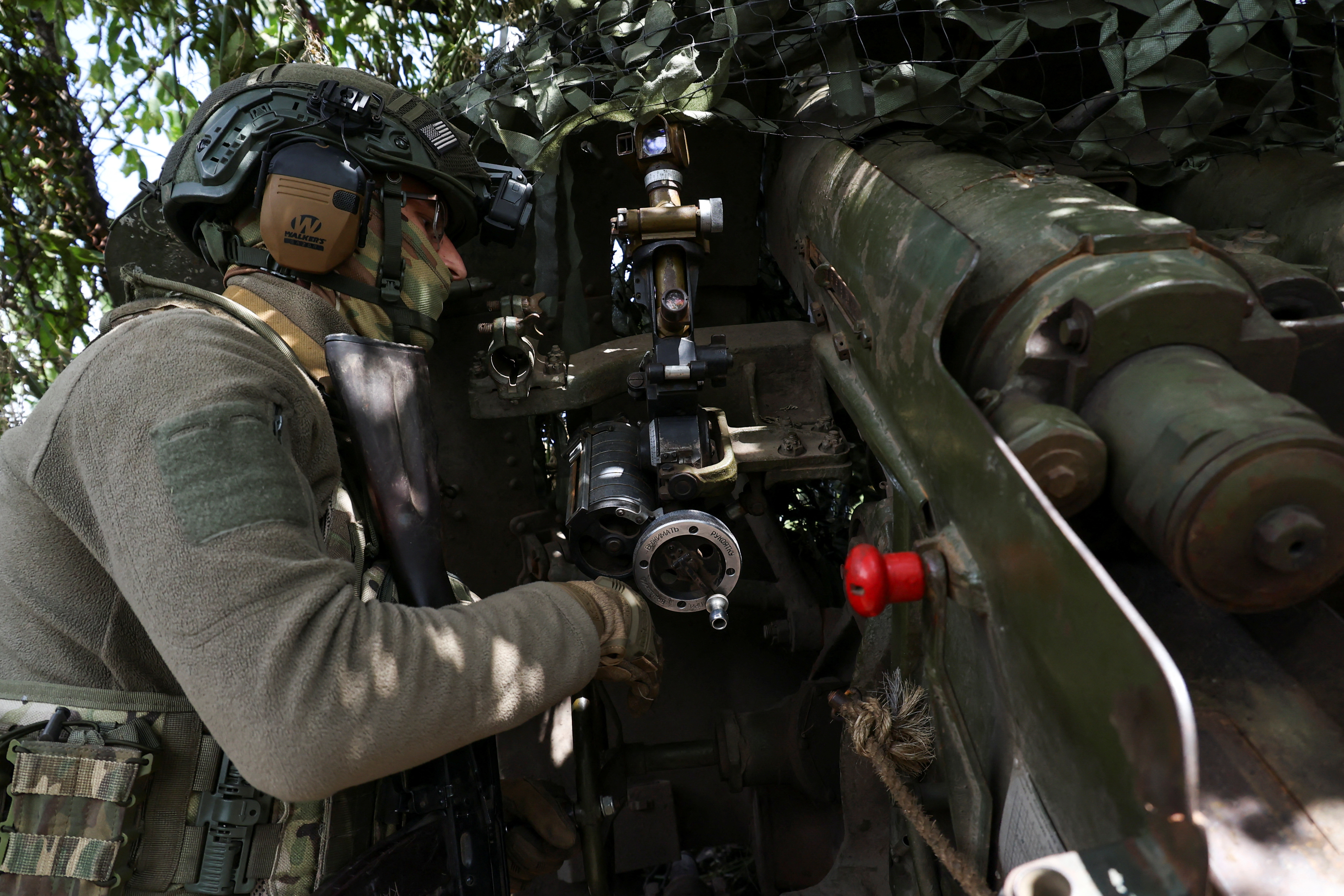 A soldier pointing a howitzer before firing it on the front lines near Bakhmut