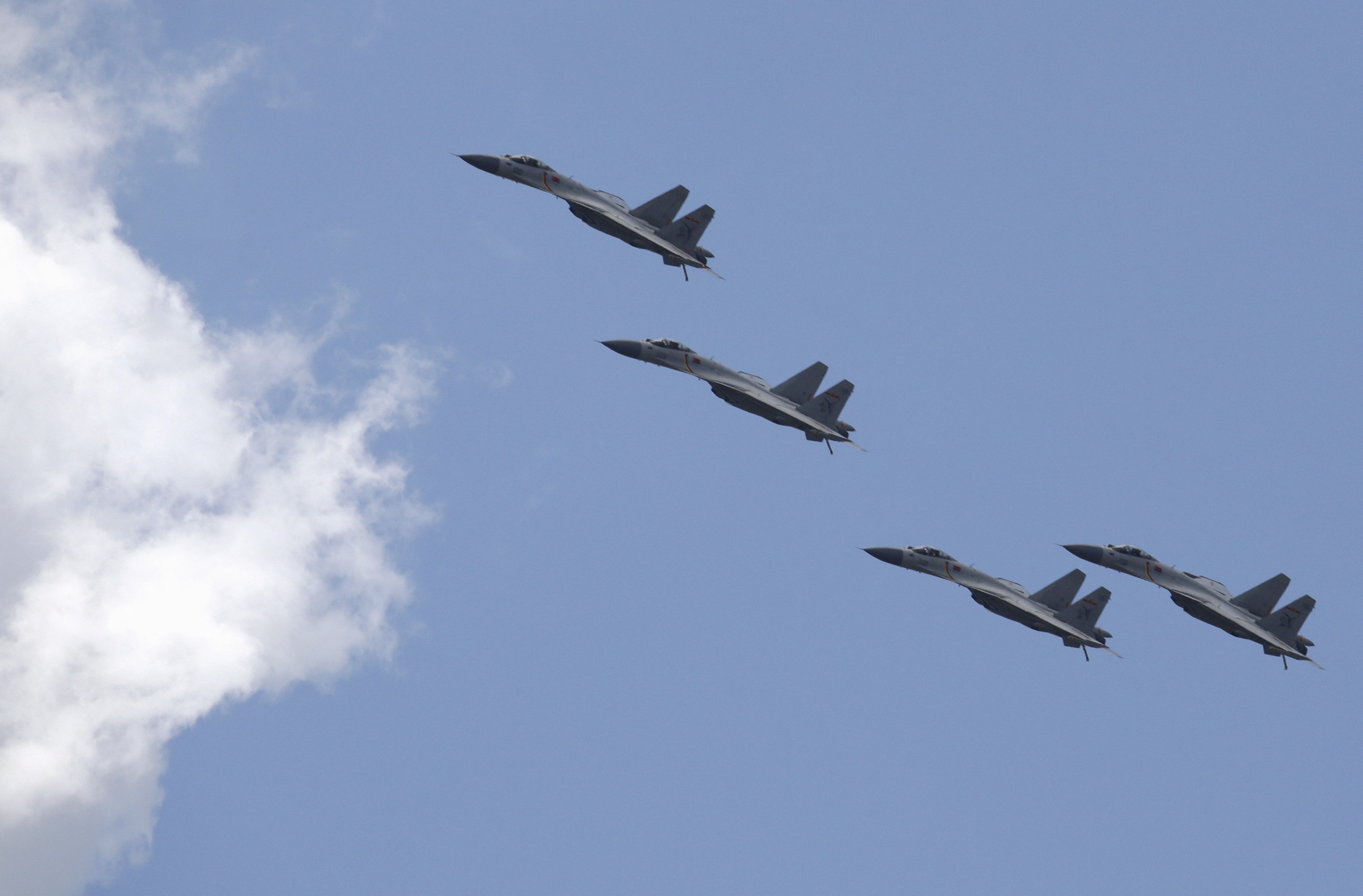 Four Chinese J-11B fighter jets flying in formation against a blue sky