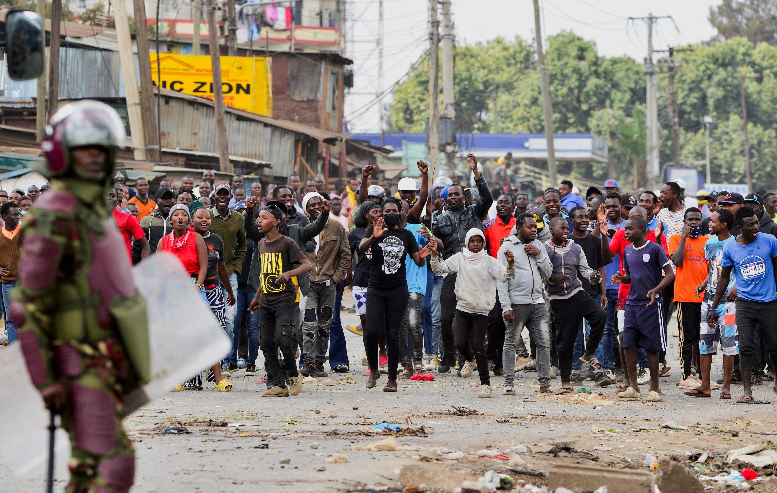 A riot police officer stands near supporters of Kenya's opposition leader Raila Odinga of the Azimio La Umoja (Declaration of Unity) One Kenya Alliance, during an anti-government protest against the imposition of tax hikes by the government, in Mathare settlement in Nairobi, Kenya, July 12, 2023.