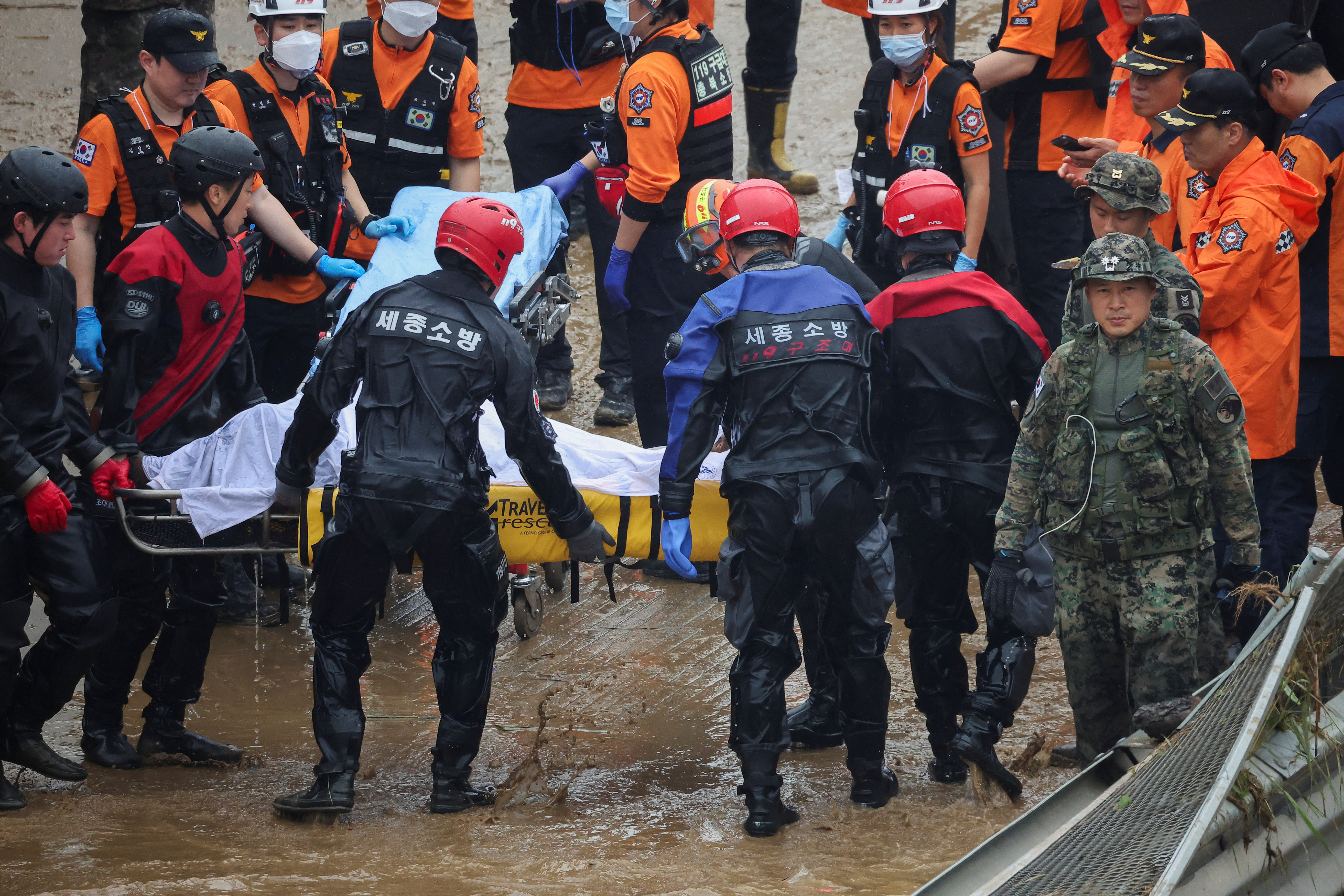 Rescue workers carry the body of a victim recovered during a search and rescue operation near an underpass that has been submerged by a flooded river caused by torrential rain in Cheongju, South Korea, July 16, 2023.