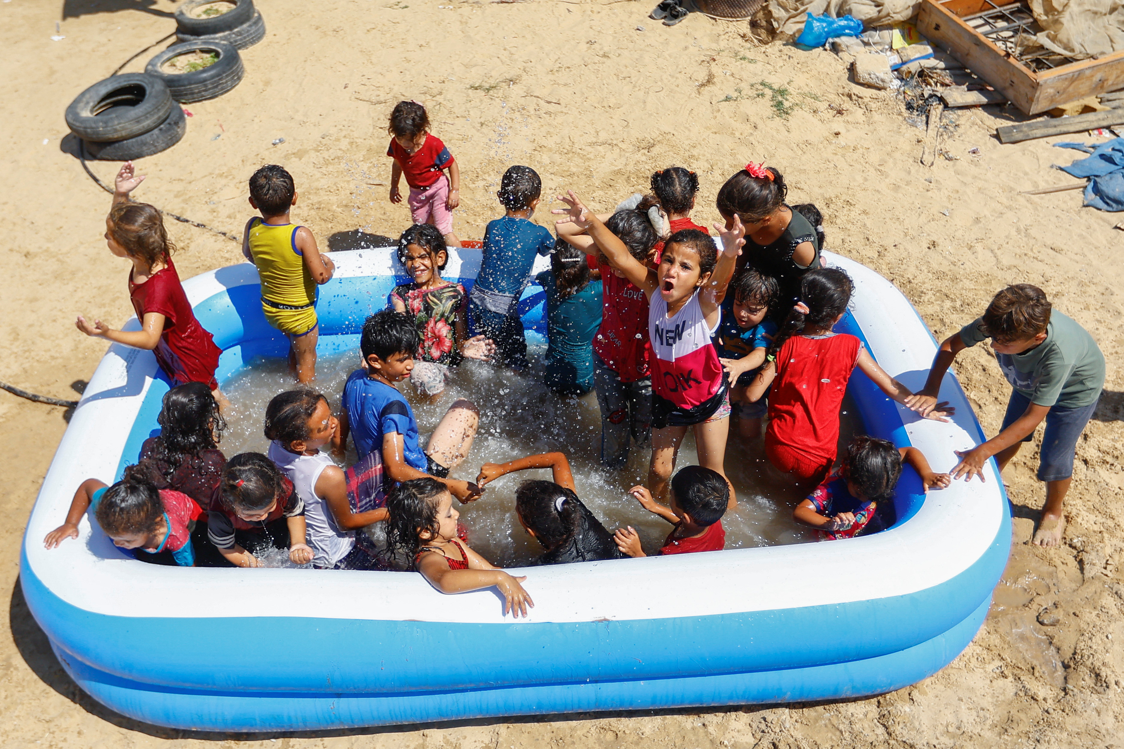Palestinian children play in a portable pool to cool down amid a heatwave as Gaza power shortages are worsened by the heat, provoking protests