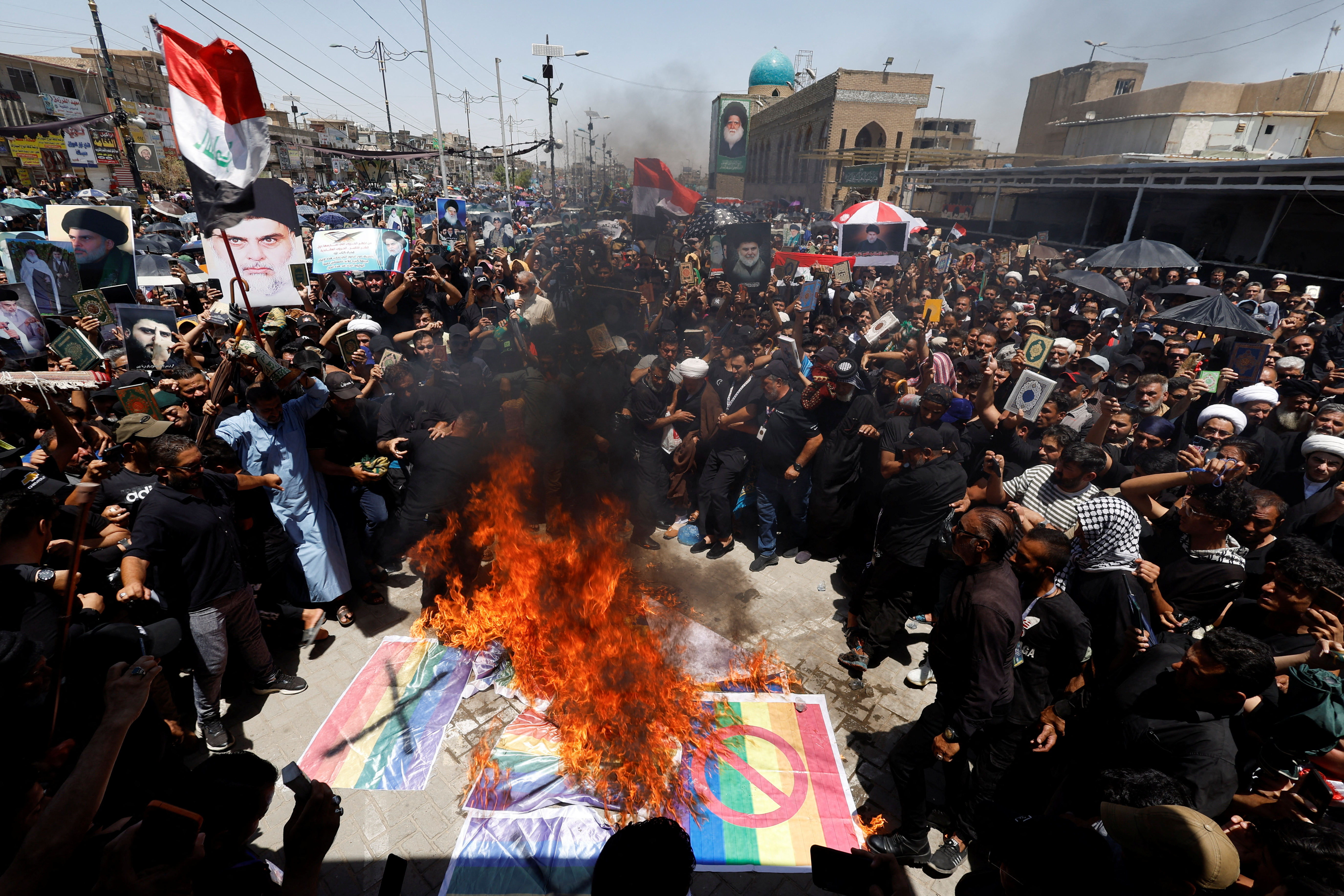 Supporters of Iraqi Shi'ite cleric Muqtada al-Sadr burn flags as they take part in a protest after the embassy was stormed and set on fire ahead of an expected Koran burning in Stockholm