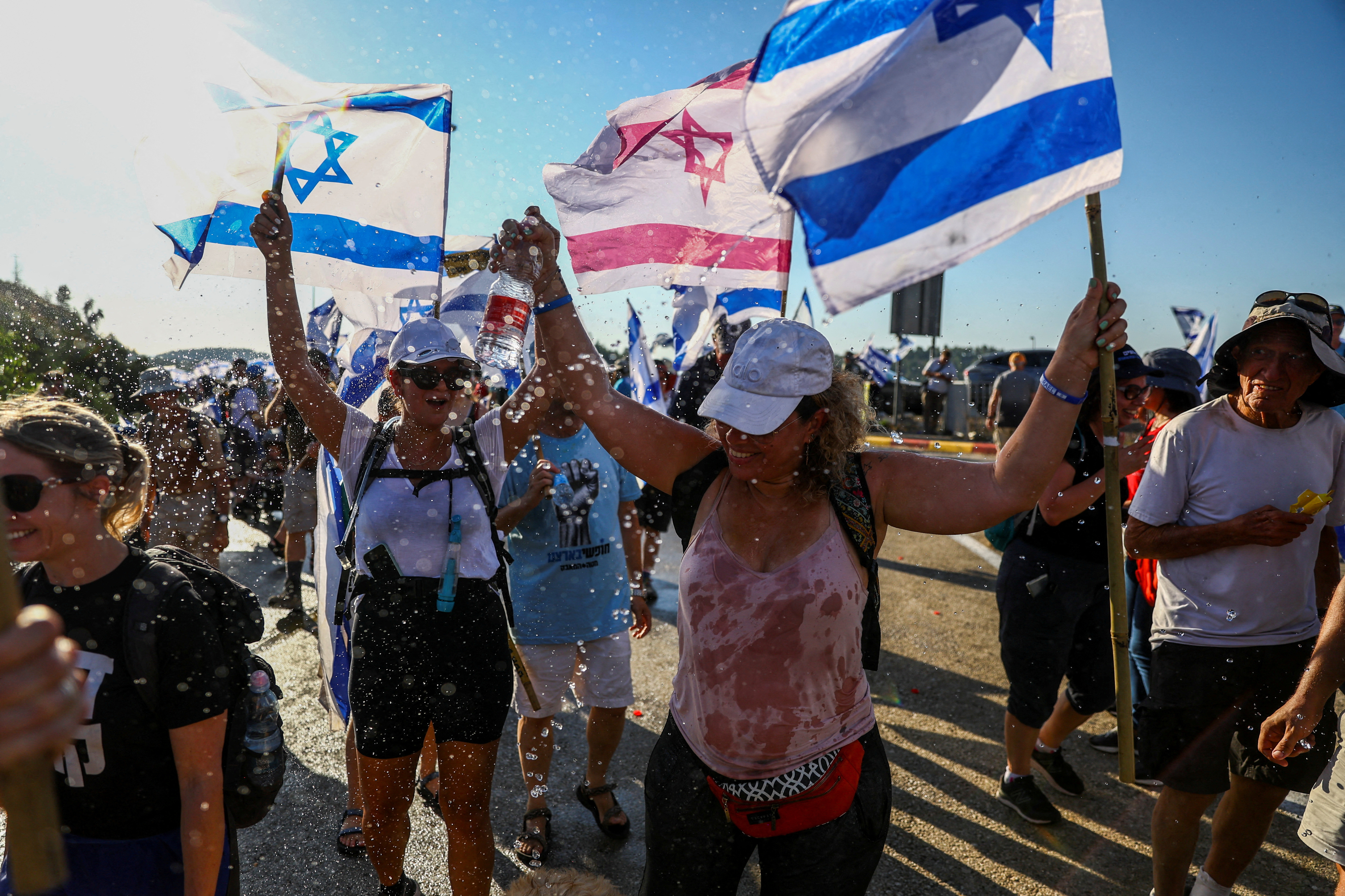 Protesters hold flags as they march in demonstration against Israeli Prime Minister Benjamin Netanyahu