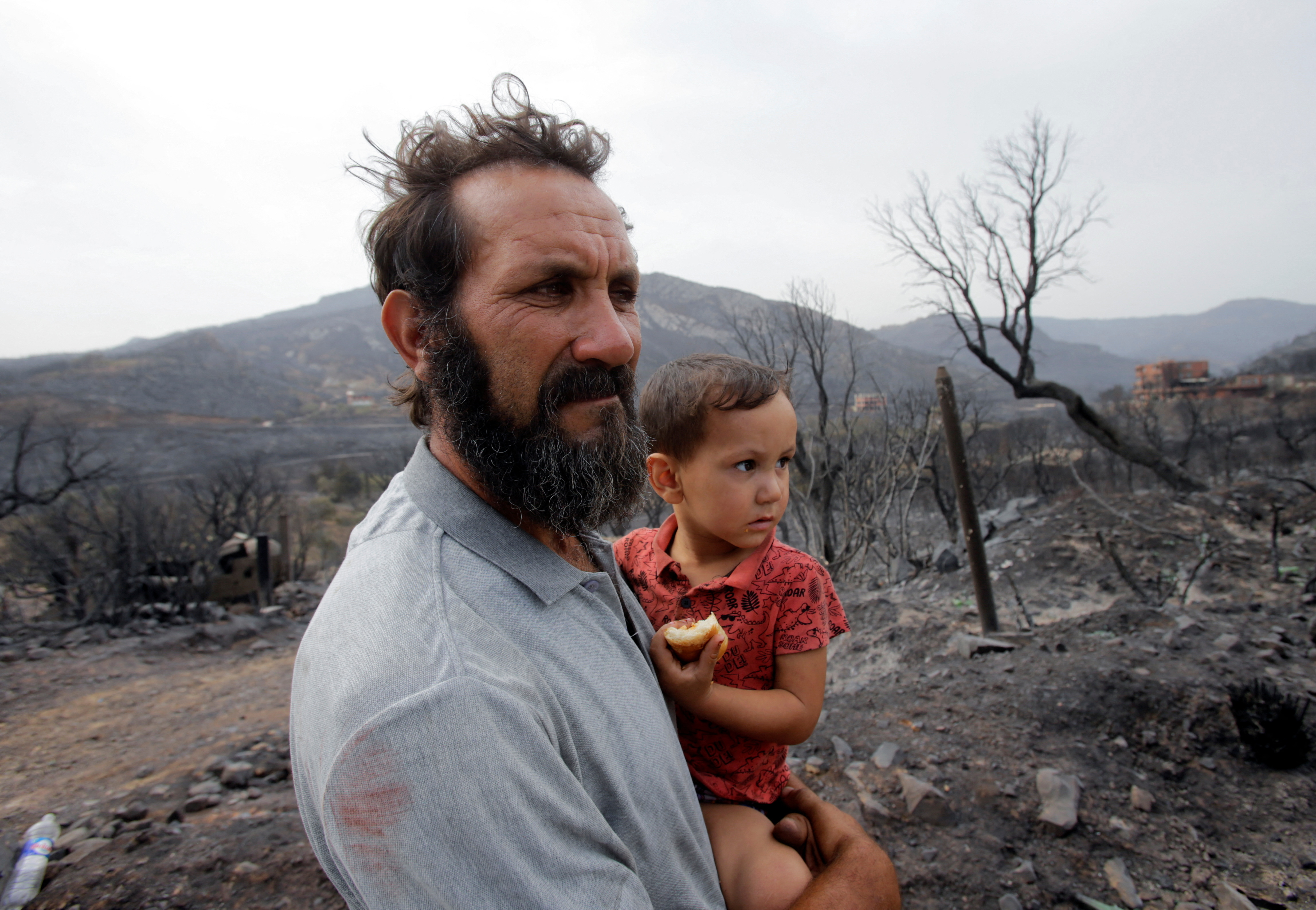 Amar Belkati, a 57-year-old farmer, carries his child
