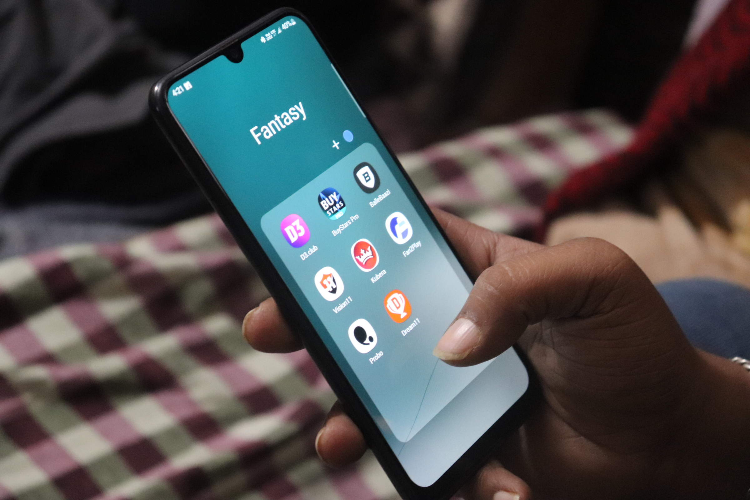 A hand holding a phone showing the different fantasy gaming apps in use in India