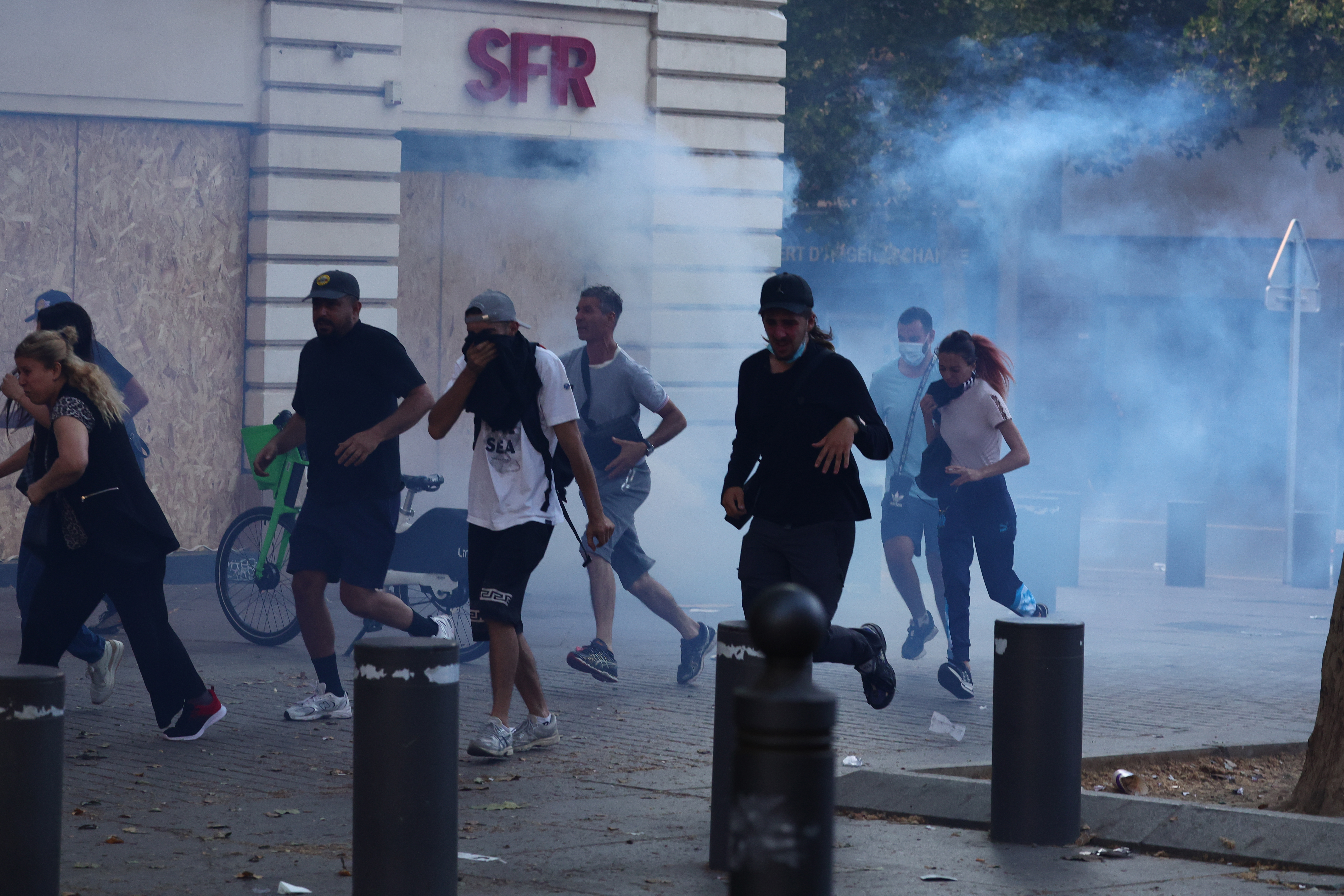 Protesters run from launched tear gas canisters during clashes with police in Marseille, southern France
