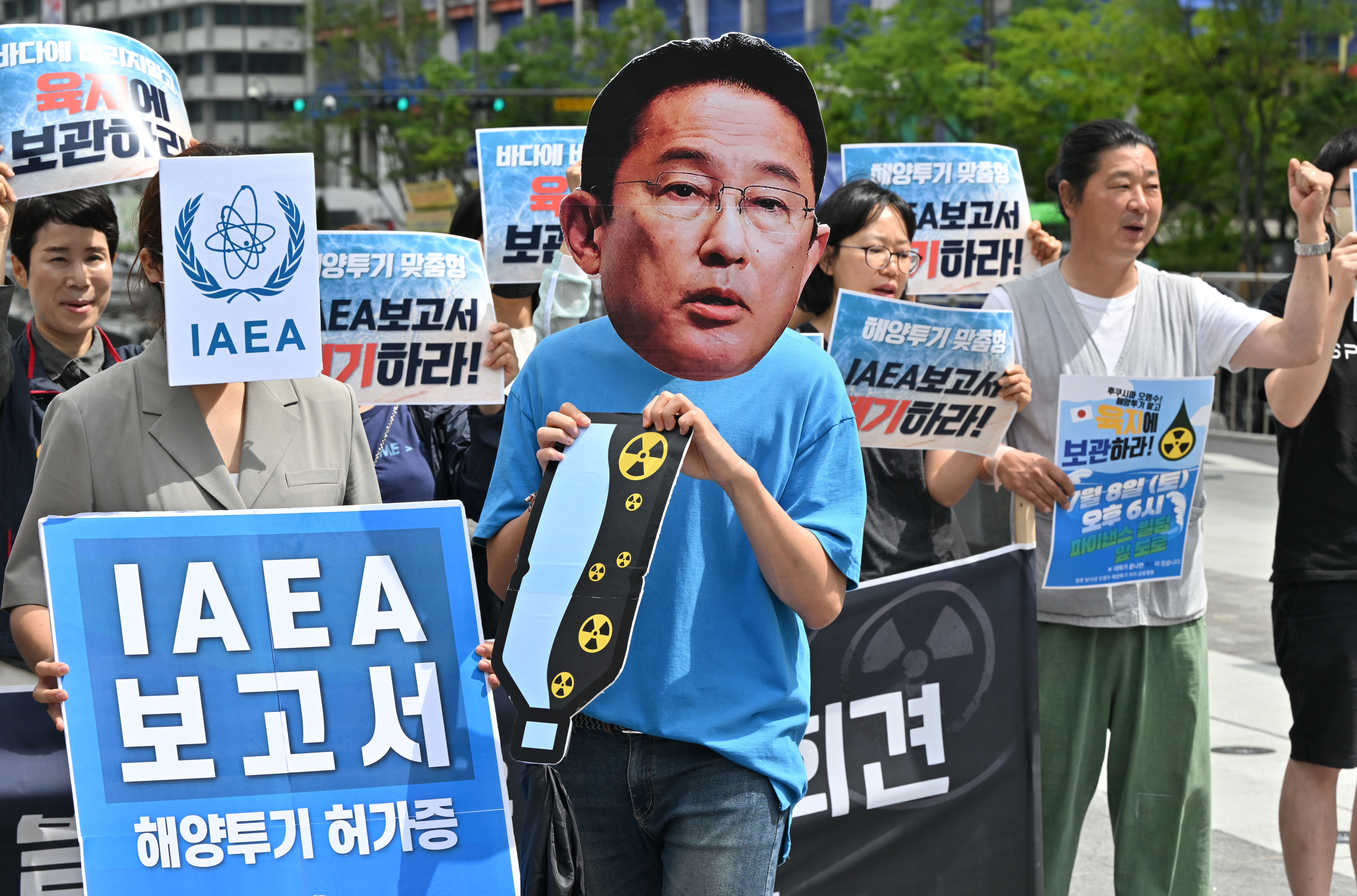 South Korean protesters hold a rally against the Fukushima water release plan. One is wearing a mask of Japanese Prime Minister Fumio Kishida. Others have placards in Korean reading IAEA 